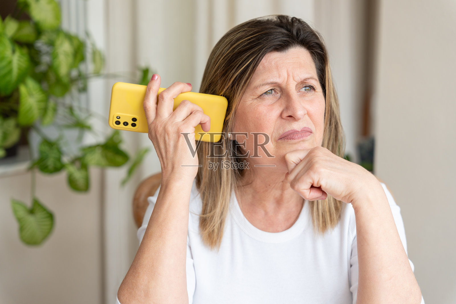 一位成熟的女性正在认真地用手机交谈,专注地倾听,脸上带着担忧和若有所思的表情照片摄影图片