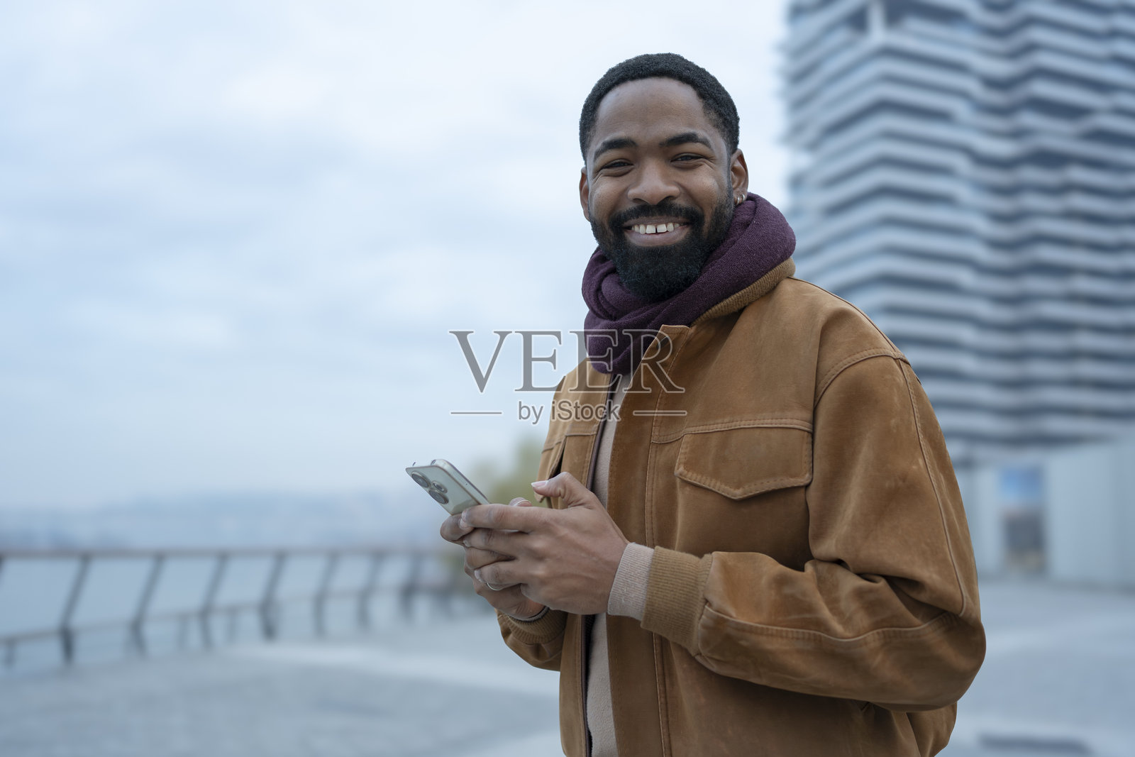 年轻的非裔美国男子在城市中使用手机微笑照片摄影图片