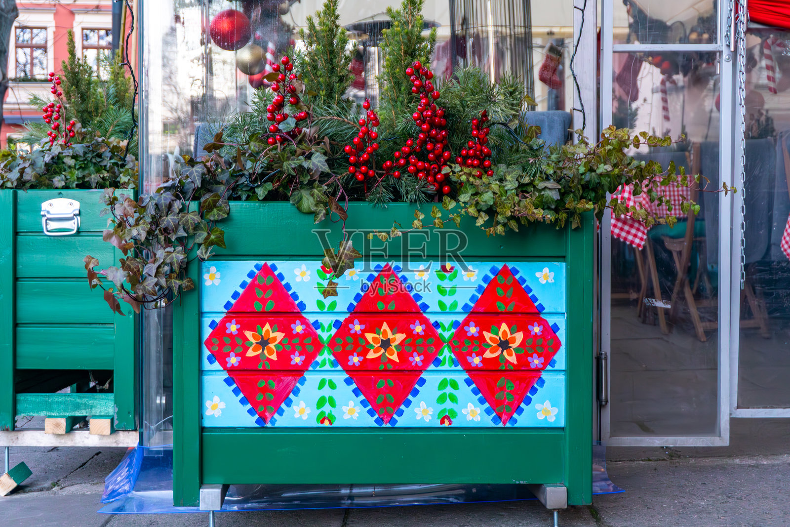 商店橱窗前摆放着一个带有民间图案的彩色户外种植箱,上面装饰着冬季植物照片摄影图片