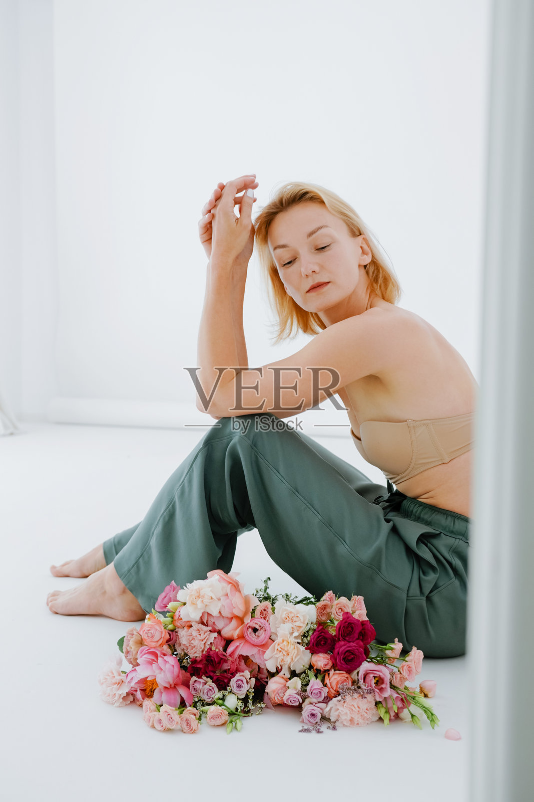 年轻美丽的女孩与工作室里的花。自信的女人与花。女士与牡丹。照片摄影图片