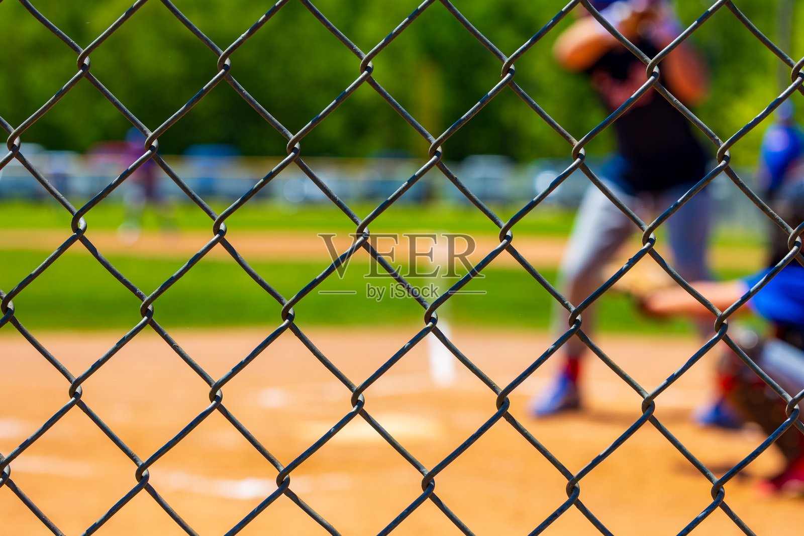 选择性聚焦于青年棒球比赛中的链式围栏,背景模糊。照片摄影图片
