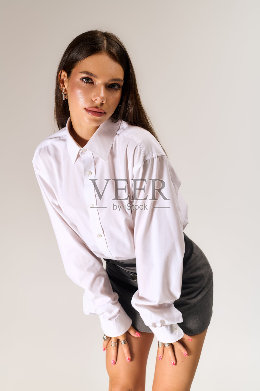 时尚年轻女性在优雅的灰色工作室背景下展示秋季时尚照片摄影图片