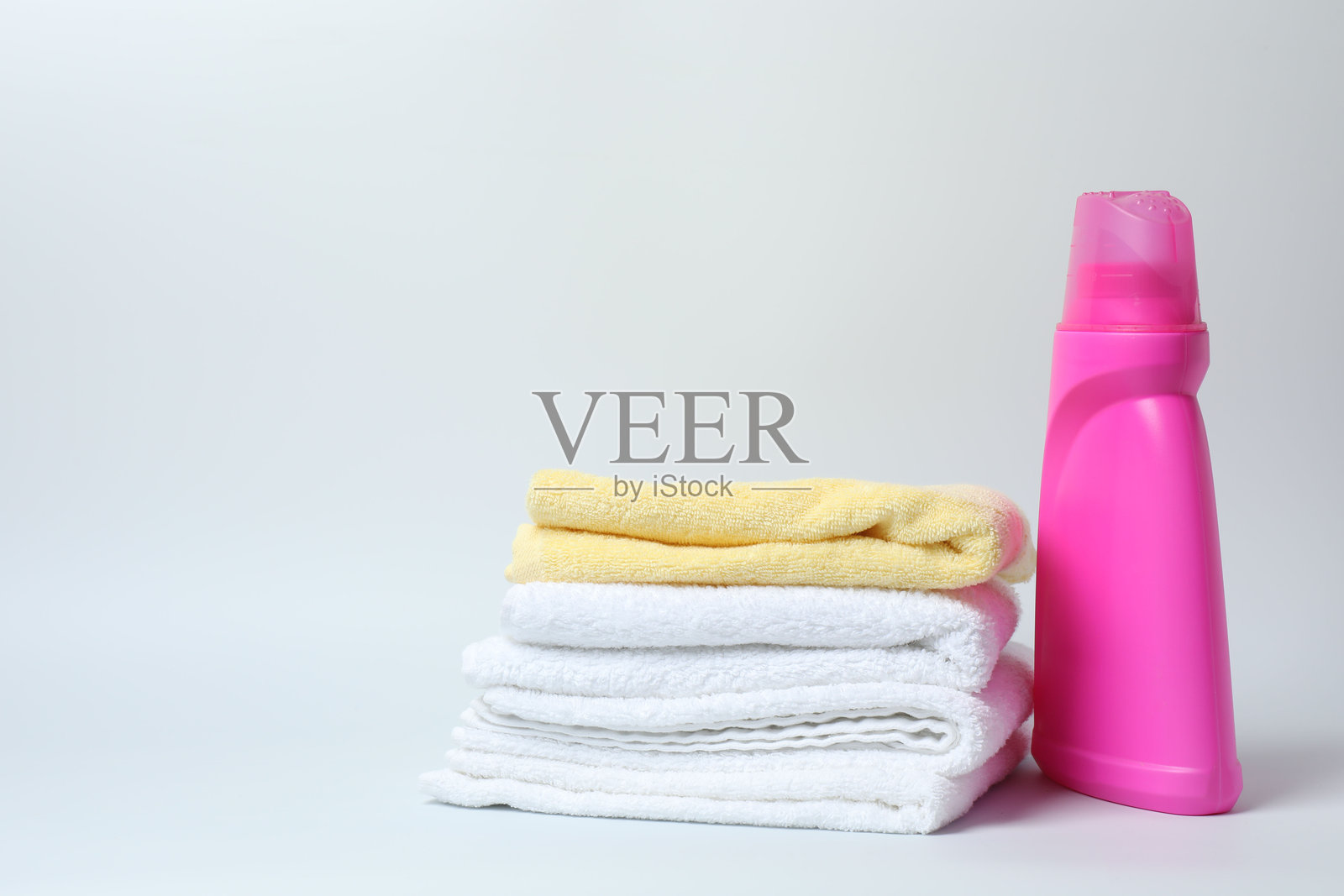 白色背景上的洗衣液瓶和一包干净的毛巾照片摄影图片