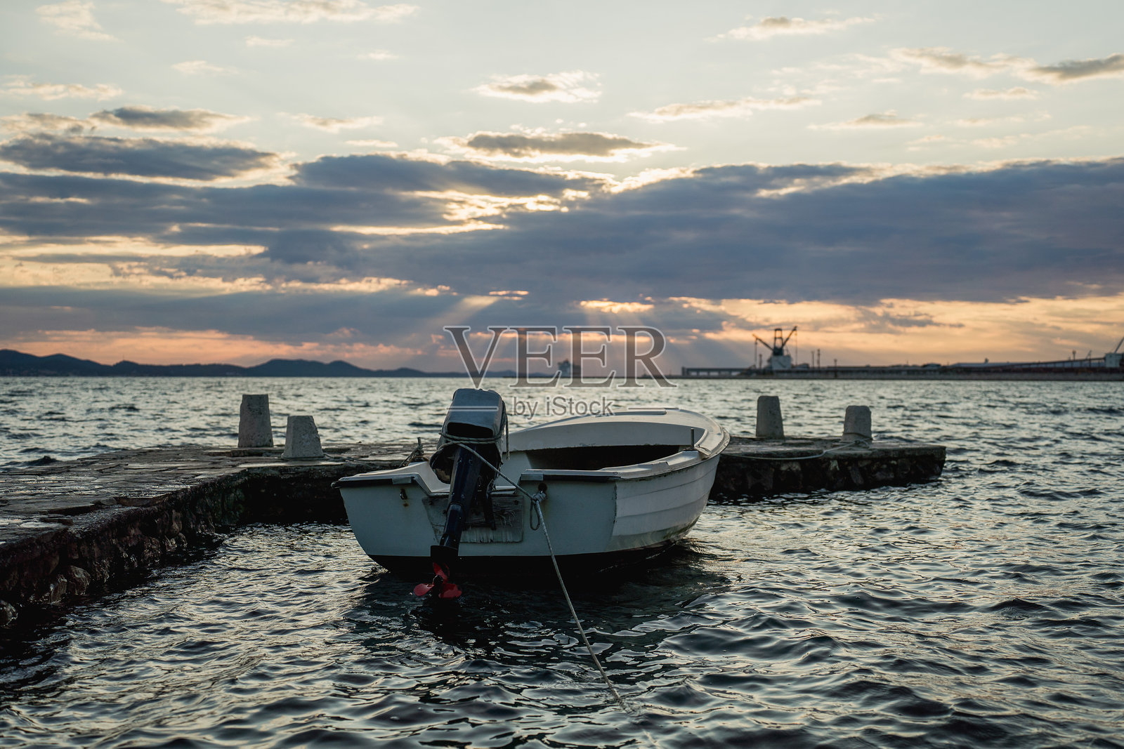 日落时分,一艘小型渔船漂浮在平静的海面上照片摄影图片
