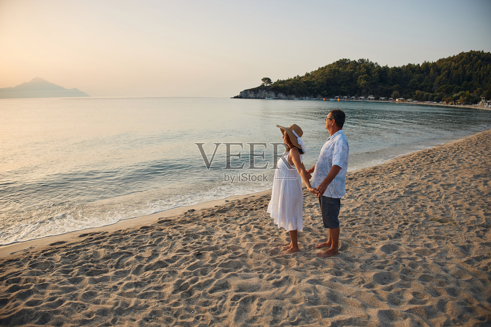 一对老年夫妇手牵手在海滩上观看日落照片摄影图片