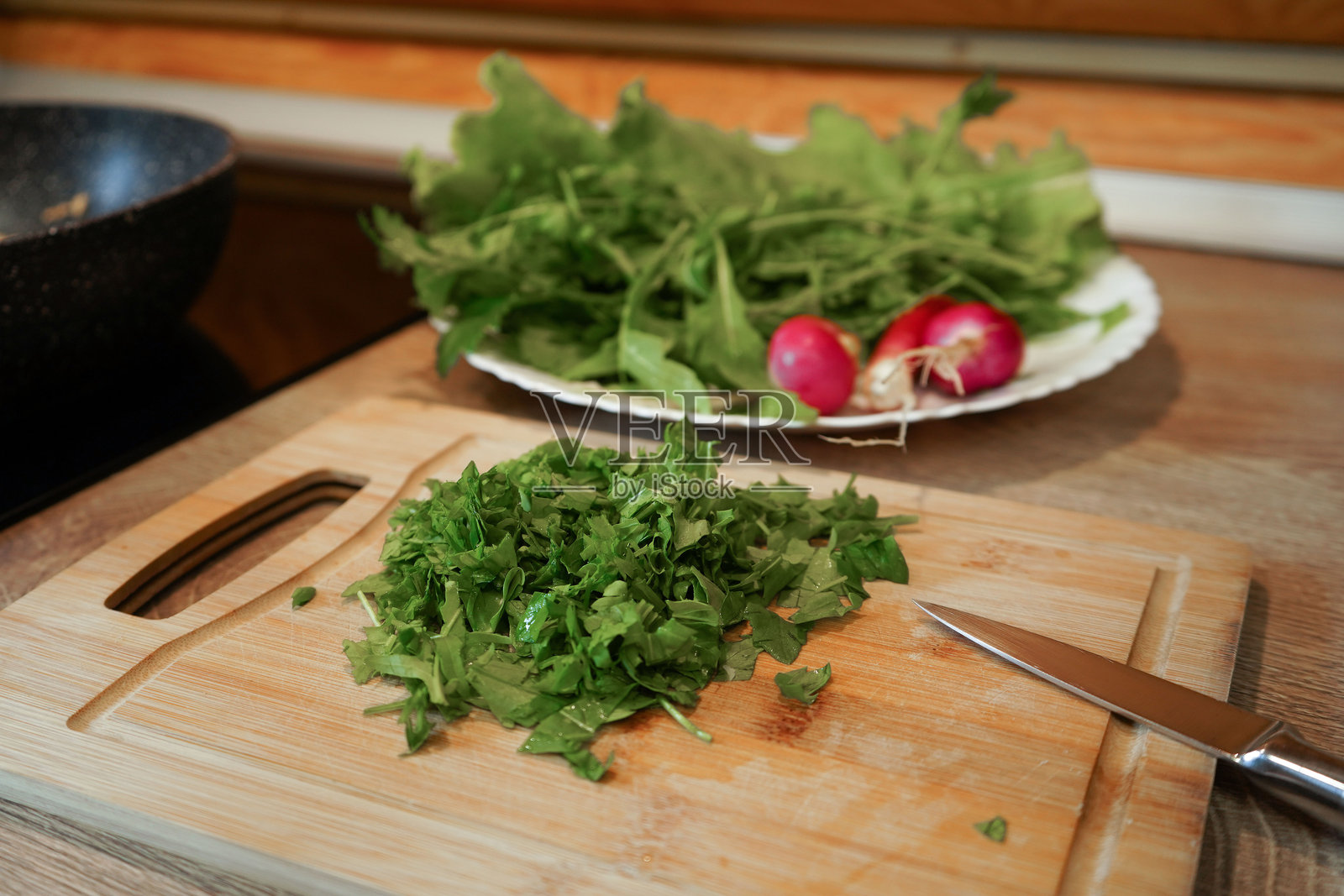 绿叶上摆放着一串红色的萝卜,这些萝卜新鲜欲滴,可以直接食用。照片摄影图片