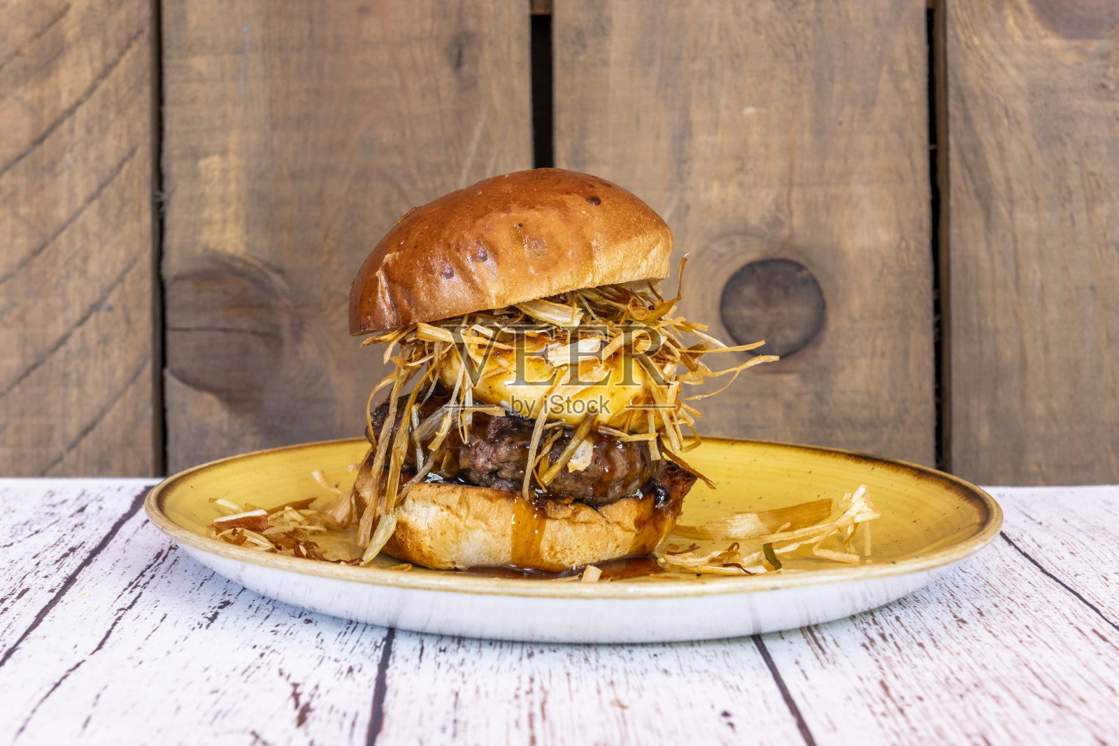 烤布里欧修面包和芝麻的美味汉堡特写,配有烤牛肉和淋着特制酱汁的酥脆培根照片摄影图片