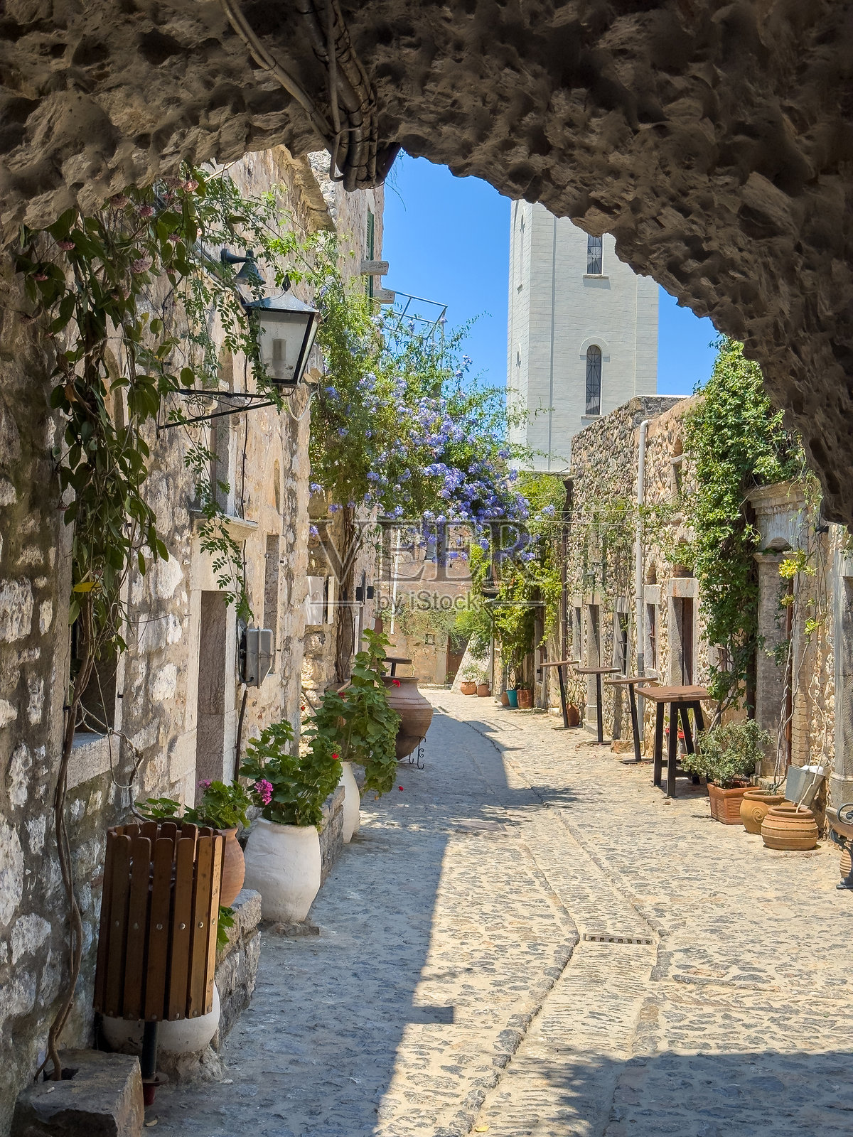 希腊希俄斯岛梅斯塔村的钟楼和鹅卵石街道。照片摄影图片