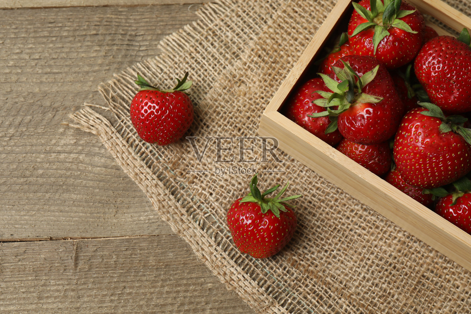托盘里的草莓放在木桌上照片摄影图片