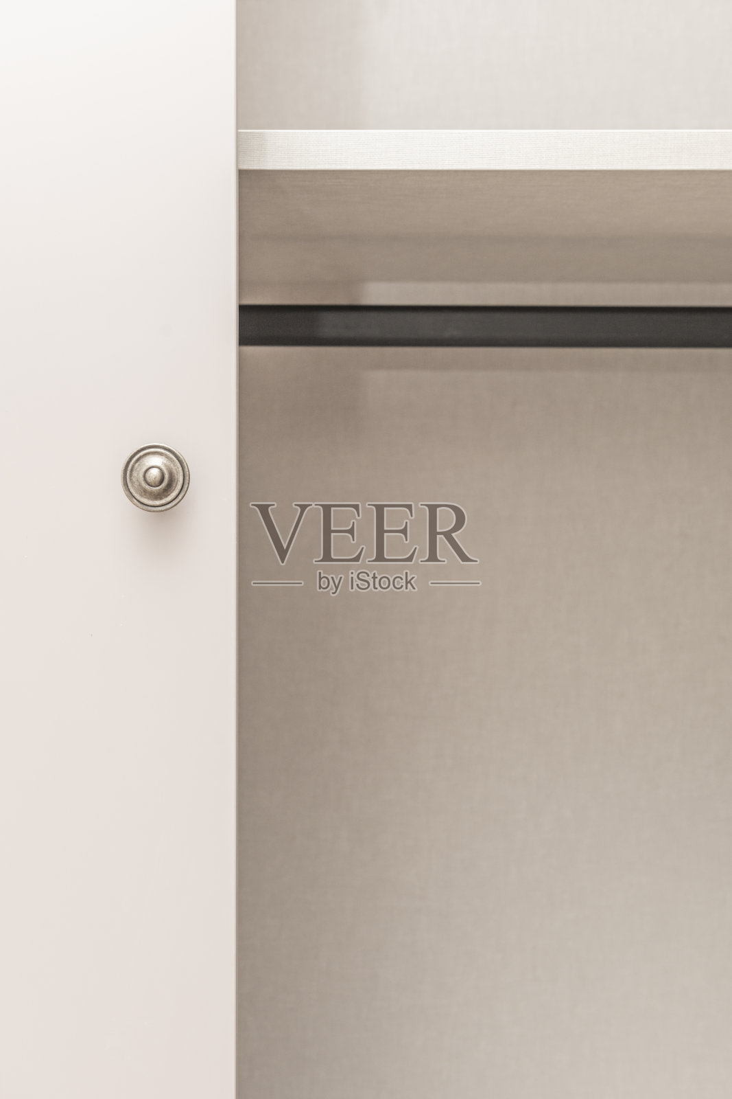 浅橡木嵌入式衣柜正面装有一系列缎面铝制球形拉手,它们都对齐在同一高度,为房间带来了干净现代的视觉节奏。照片摄影图片