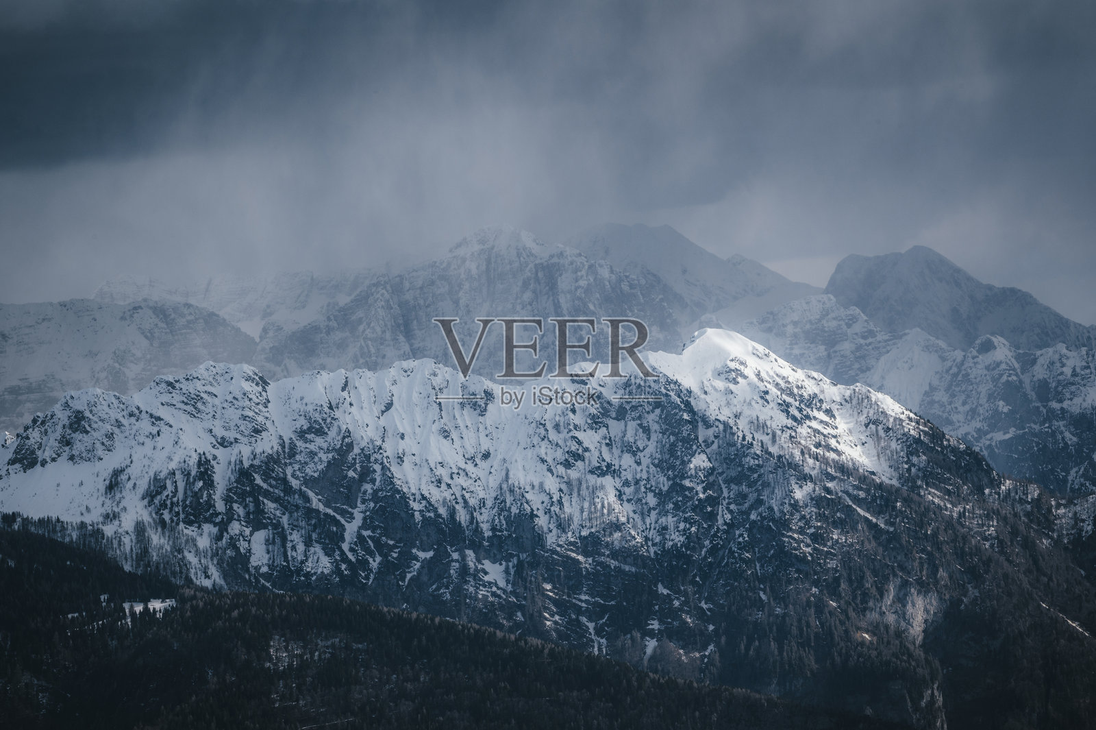 阴天冬季山景。阿尔卑斯山在雨雪天气中。照片摄影图片