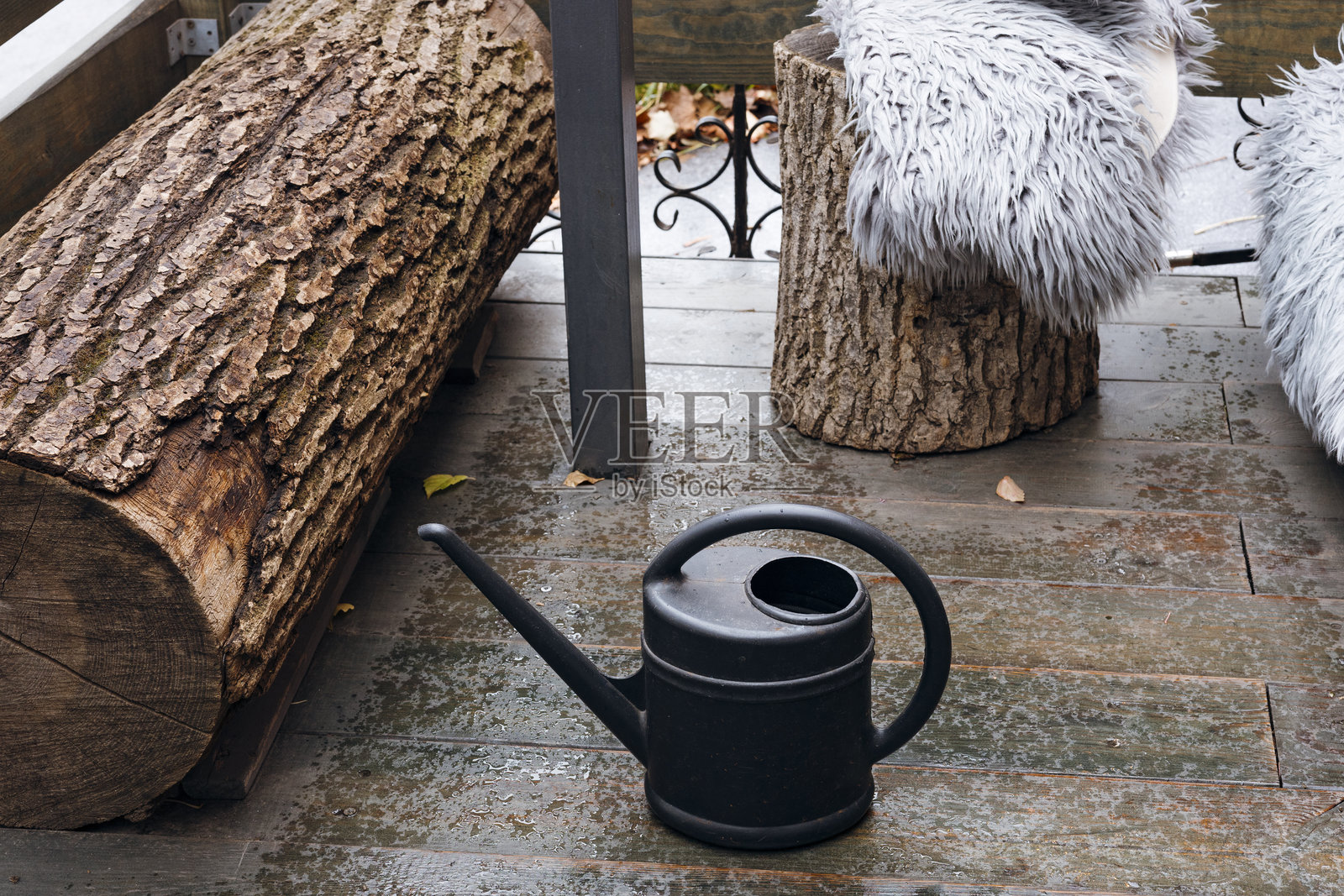 特写:一个黑色洒水壶放在后院的地面上,乡村花园风格。照片摄影图片