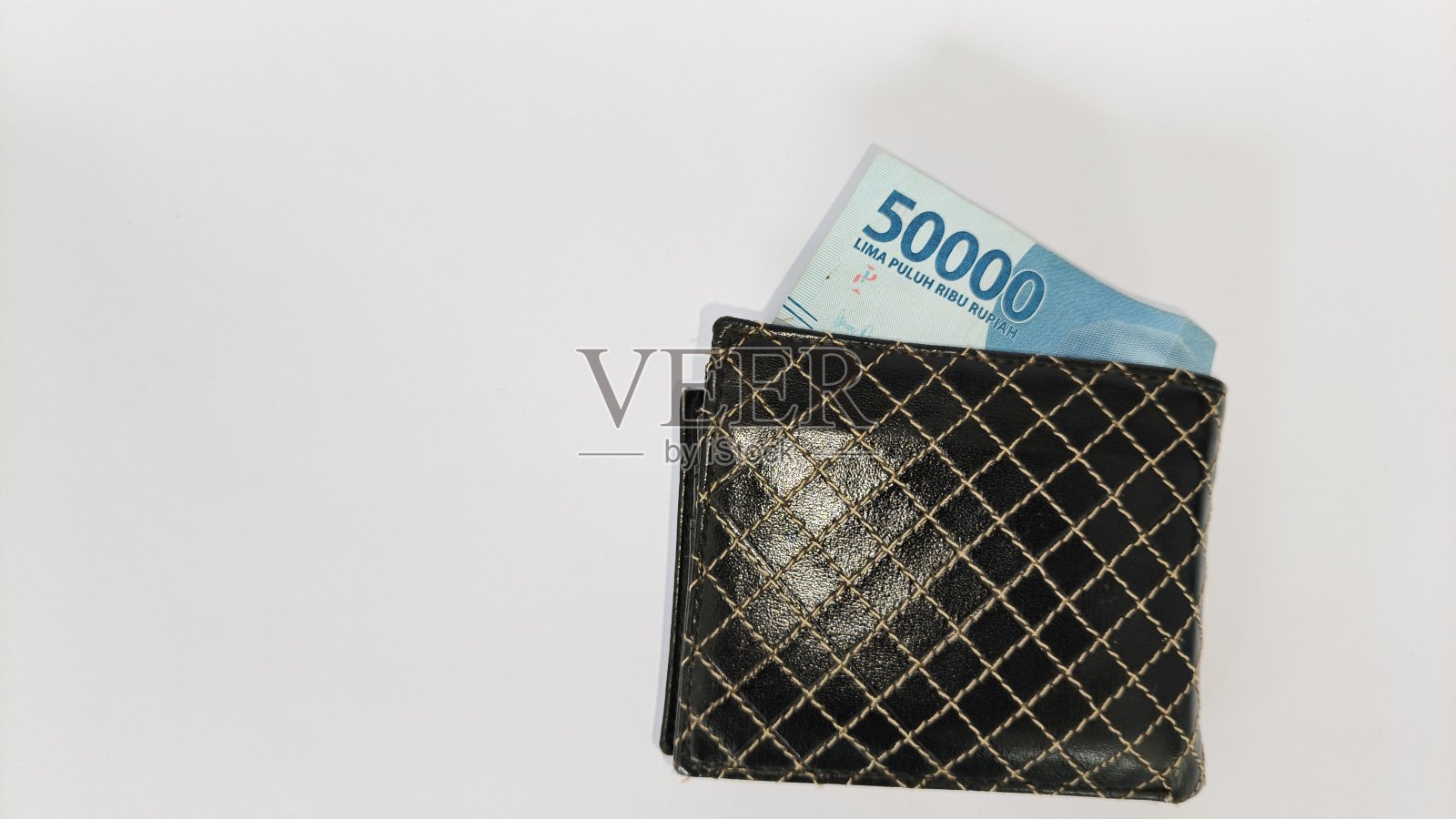 白色背景上装满印尼卢比纸币的黑色皮质钱包。照片摄影图片