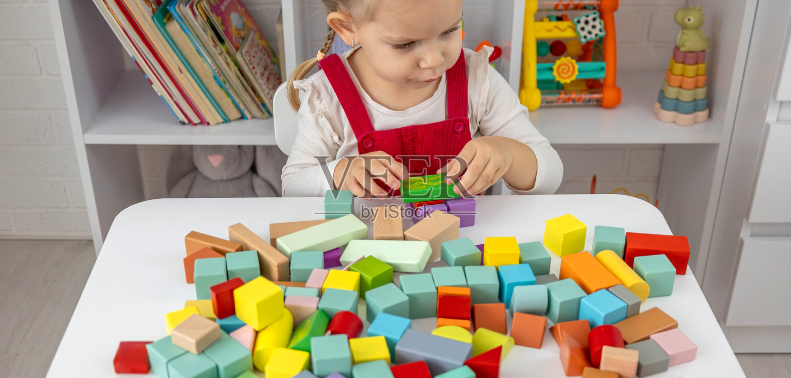 小女孩在玩多彩的木制积木,在家进行益智游戏。照片摄影图片