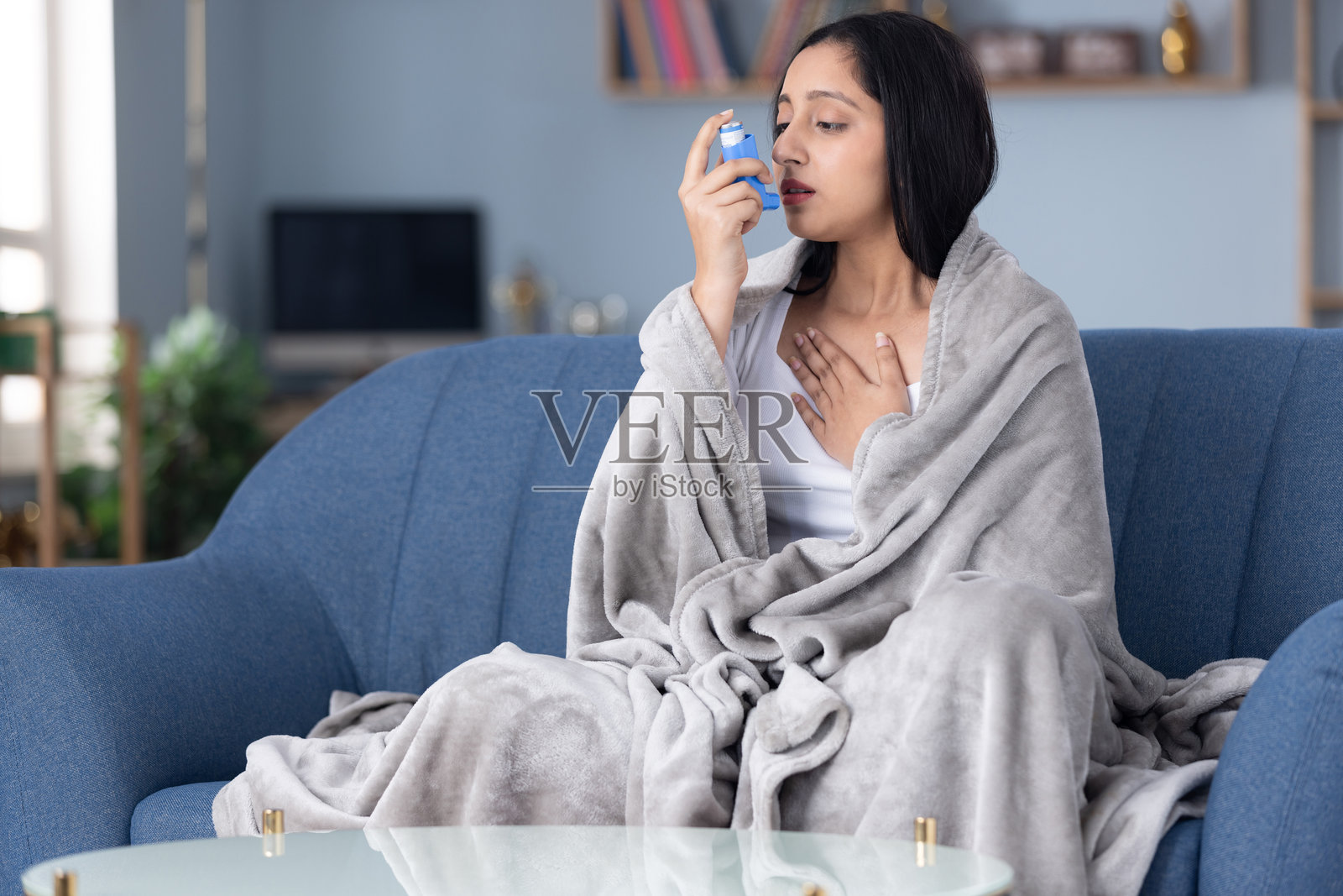 哮喘女性在家中沙发上使用吸入器照片摄影图片