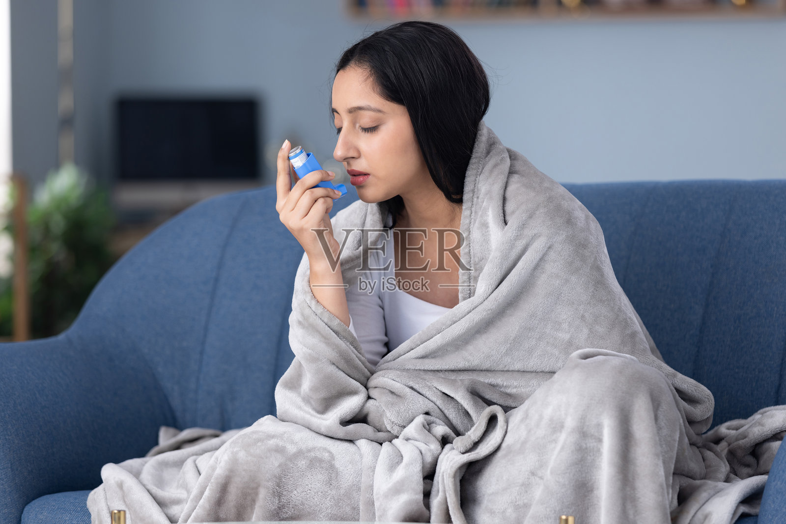 患哮喘的女性在家中沙发上使用吸入器照片摄影图片