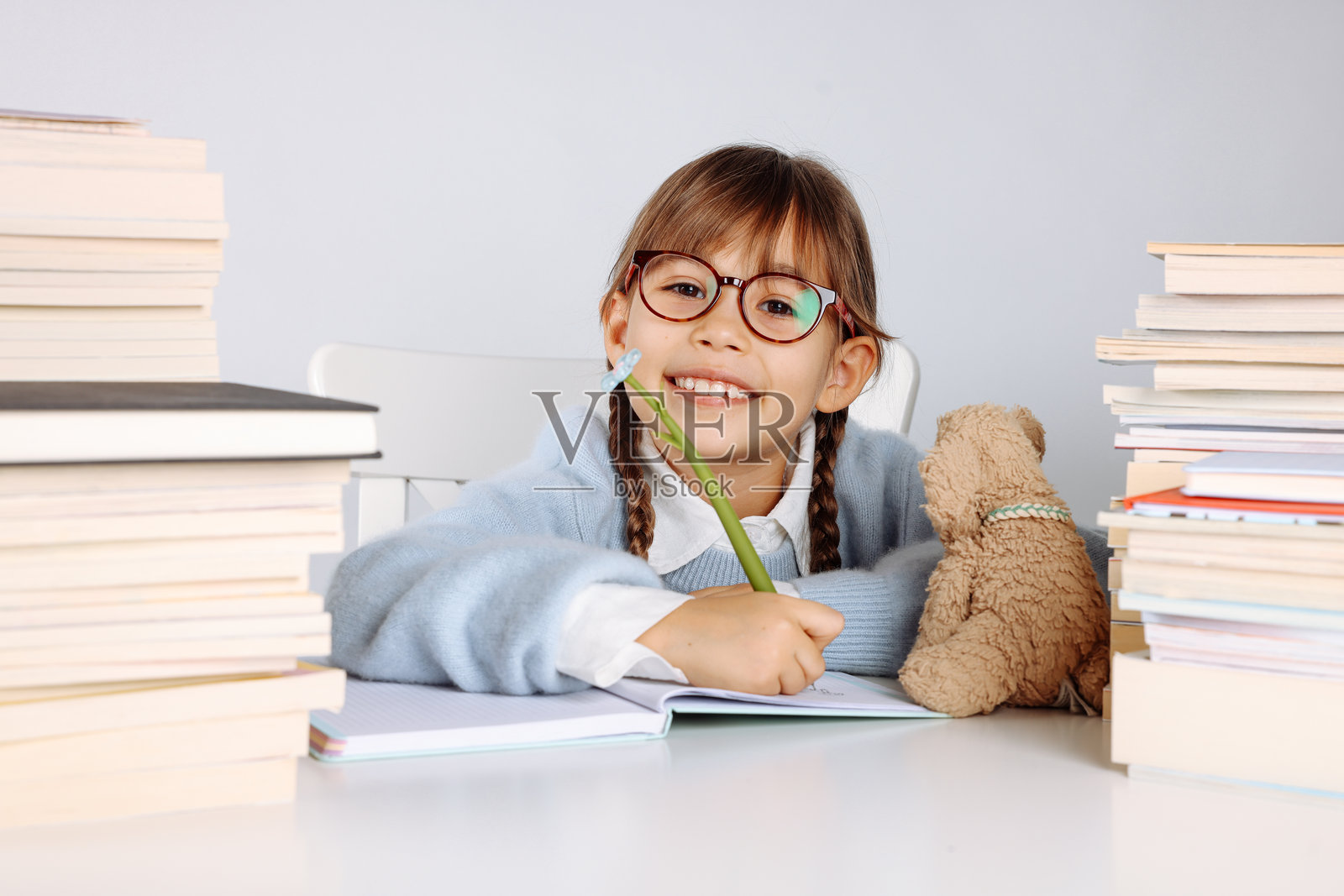 金发辫子小女生微笑着抱着一叠书照片摄影图片