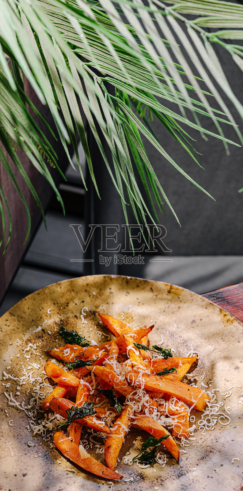 乡村风味的烤红薯,放在一个质朴的盘子上,背景有绿植点缀照片摄影图片