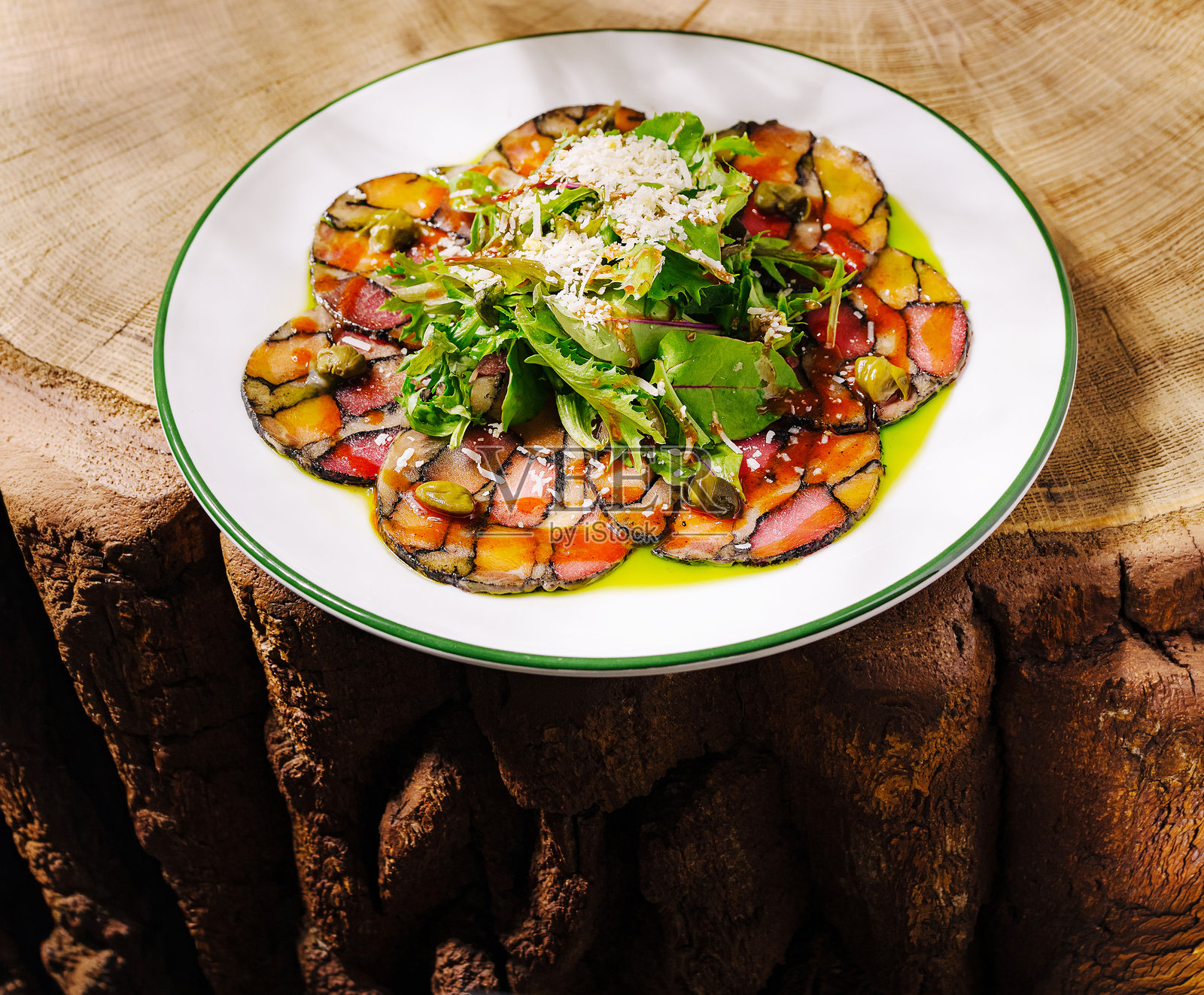 色彩缤纷的蔬菜薄片(卡帕乔)盛放在质朴的木桌上,配有绿叶蔬菜照片摄影图片