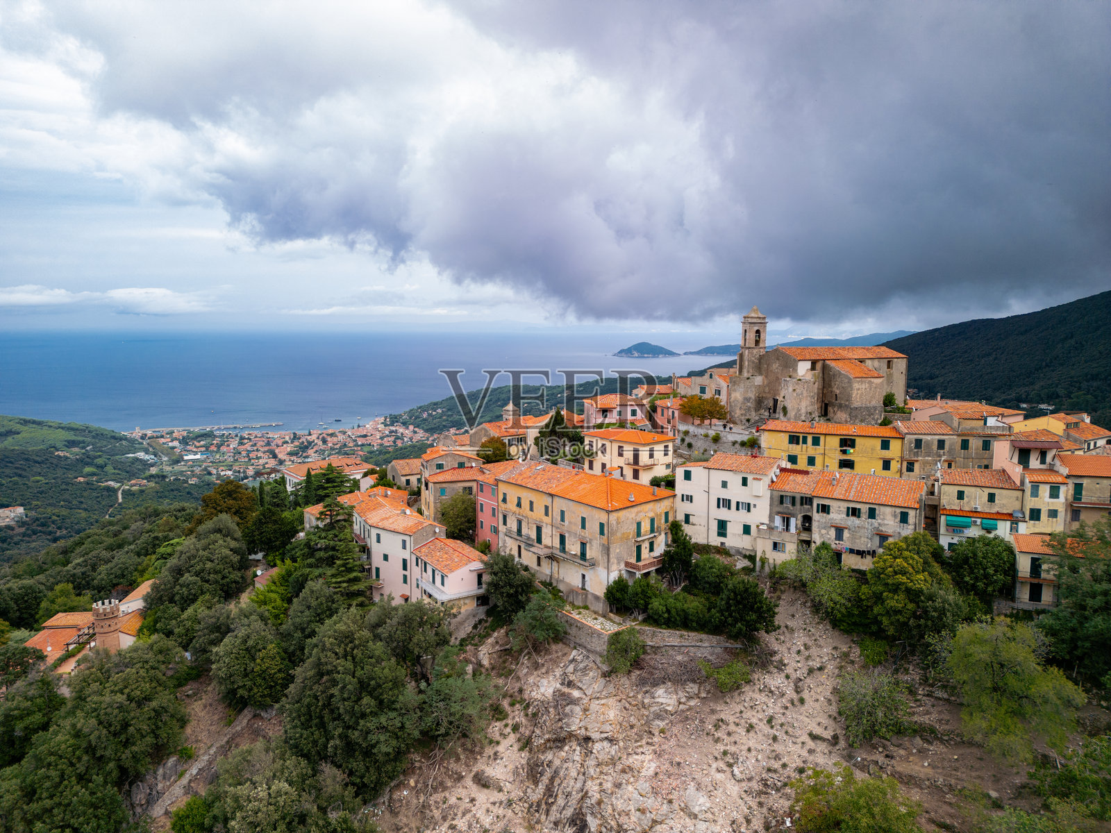 迷人的山顶村庄,色彩缤纷的房屋俯瞰地中海,四周绿意盎然,天空戏剧性地变换着色彩。地点:意大利厄尔巴岛照片摄影图片