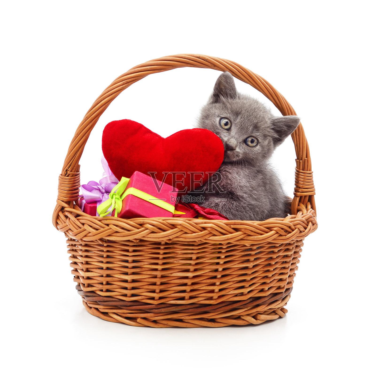 灰色小猫抱着红色爱心和礼物坐在篮子里。照片摄影图片