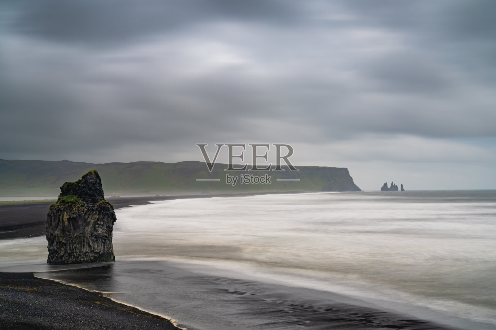 冰岛海岸的黑色沙滩,迪霍拉艾(Dyrholaey)的标志性雷尼斯岩(Reynisdrangar)海蚀柱在背景中照片摄影图片