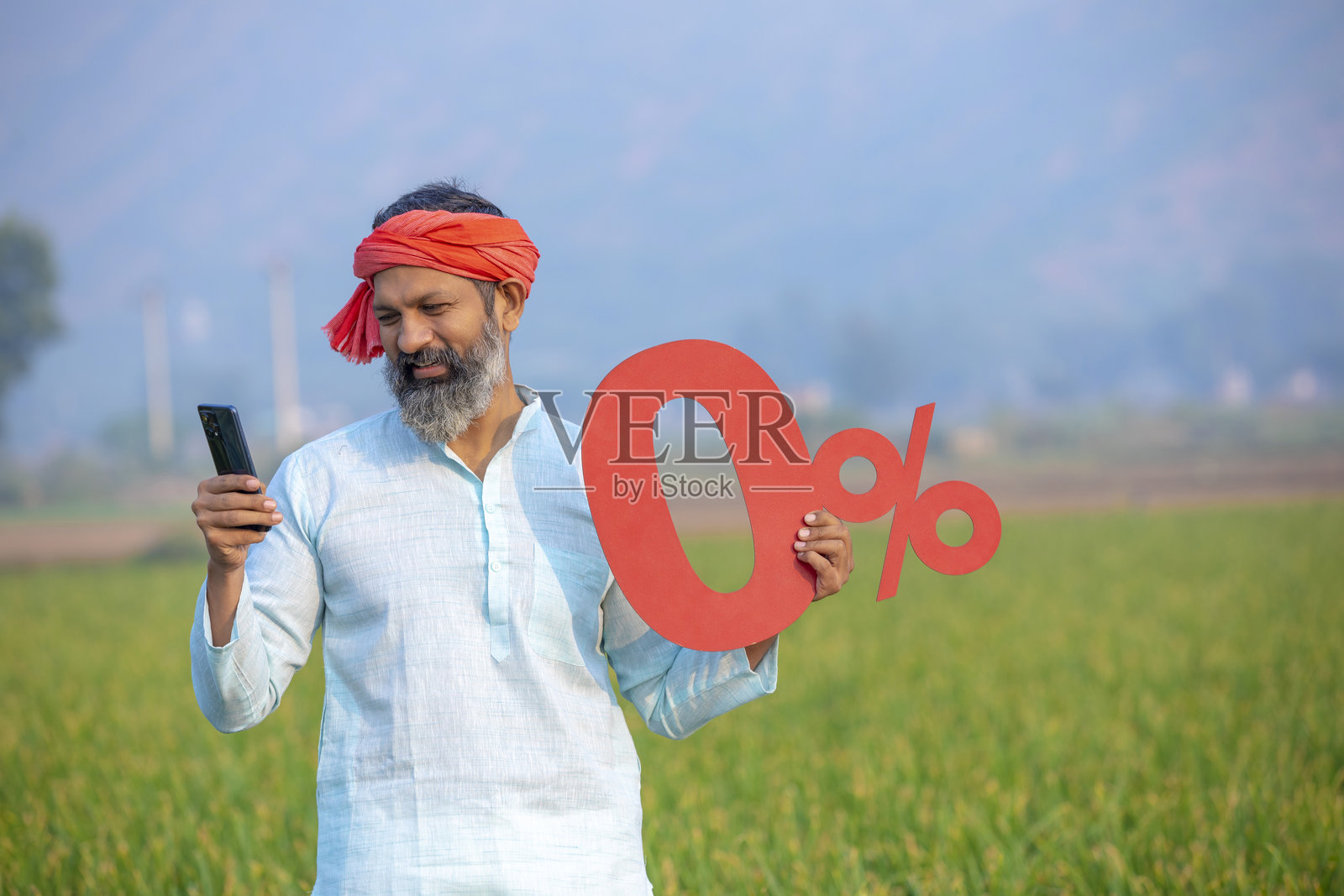 印度农民在农田里使用智能手机并展示零百分比的标牌。照片摄影图片