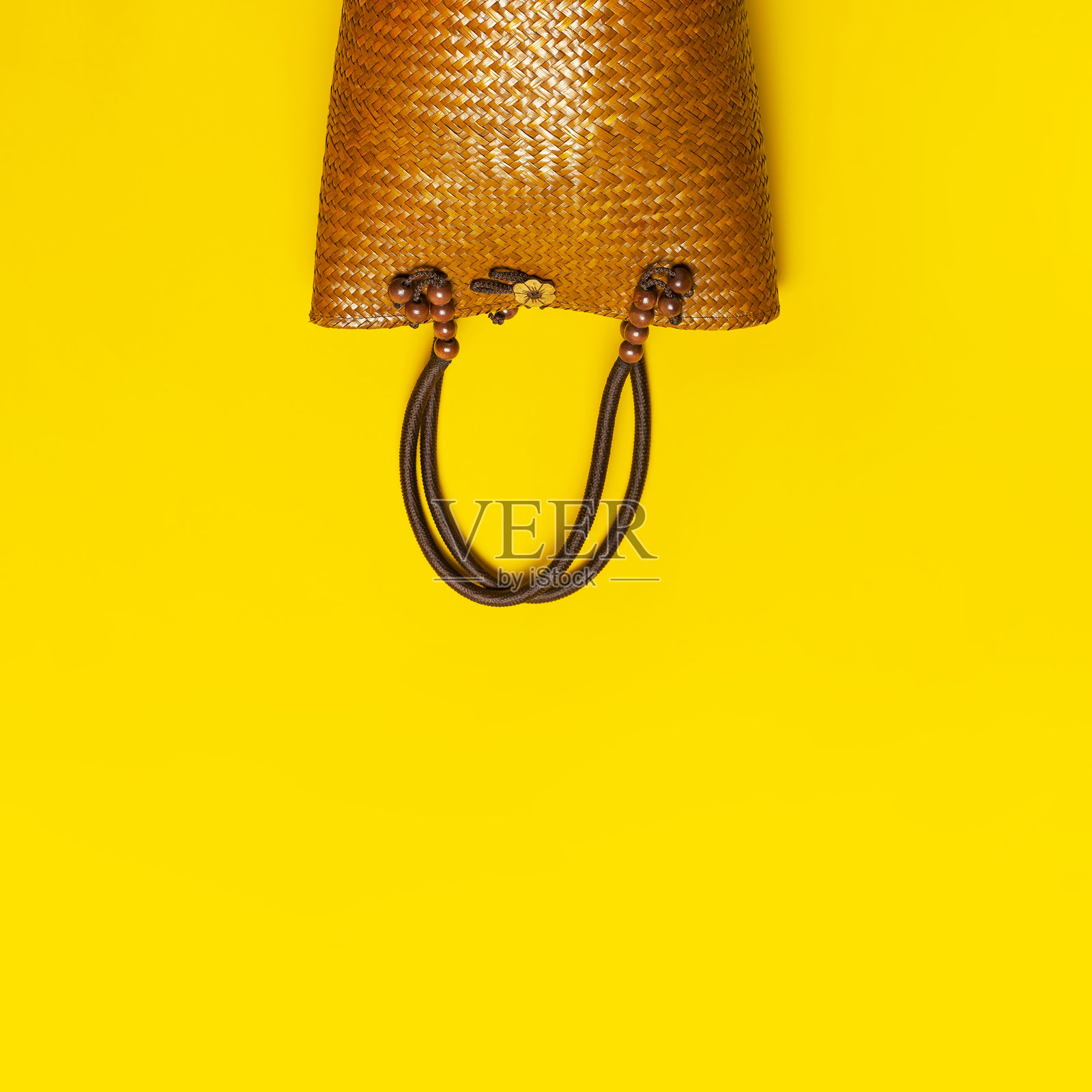 黄色背景上的海滩柳条草编或藤编女士环保包。俯视平面图,有复制空间。旅行概念。夏日明亮背景。沙滩配饰、女士夏日包、手提包、时尚照片摄影图片