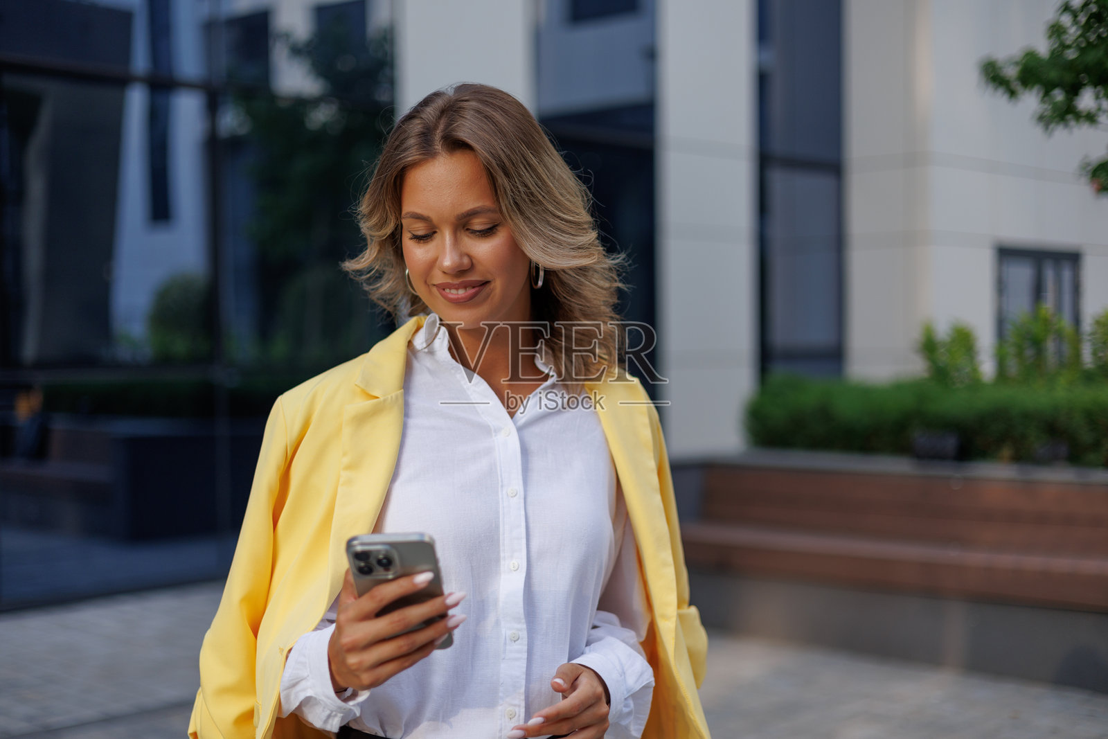 年轻的女商人在现代化办公楼前使用手机查看信息照片摄影图片