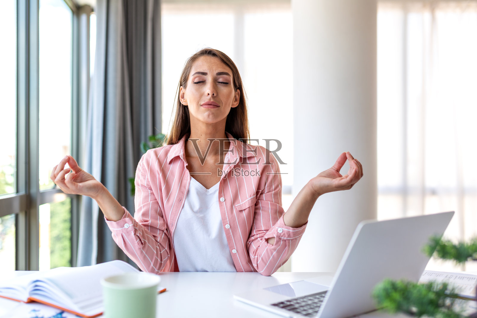 商务减压,年轻女子在办公桌前冥想,应对工作压力问题,健康与医疗理念。迷人的女商人坐在禅意办公室姿势,闭着眼睛。照片摄影图片