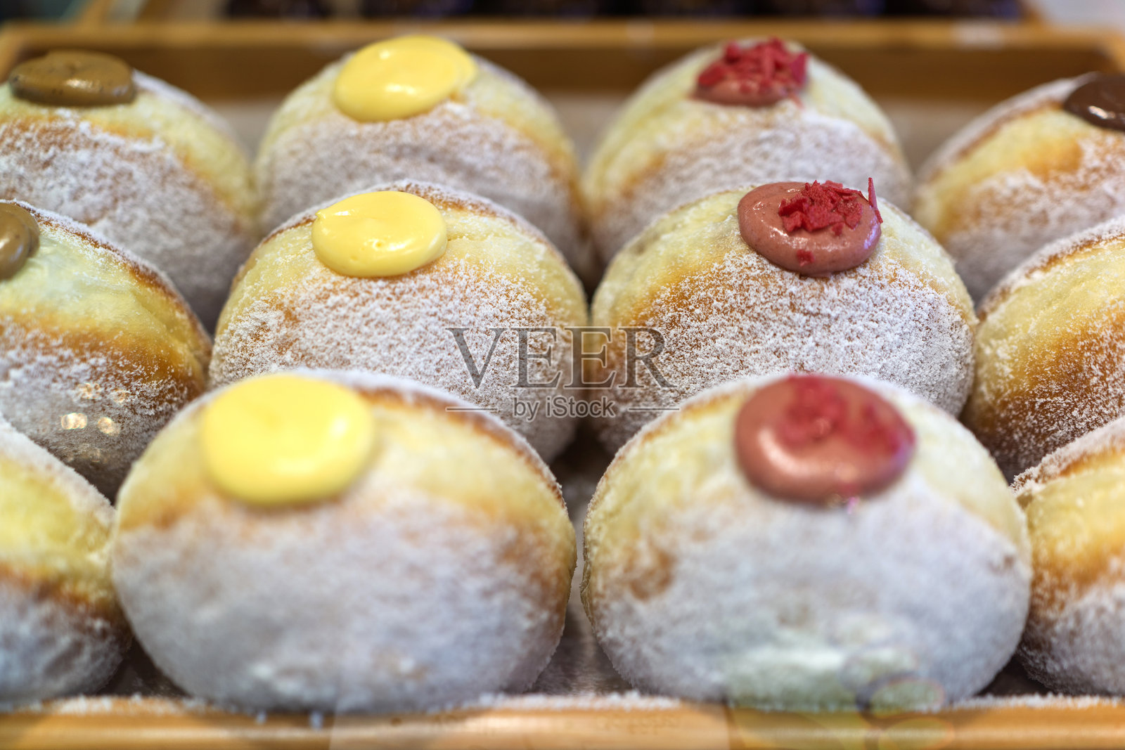 展示在面包店托盘里的各种奶油甜甜圈照片摄影图片