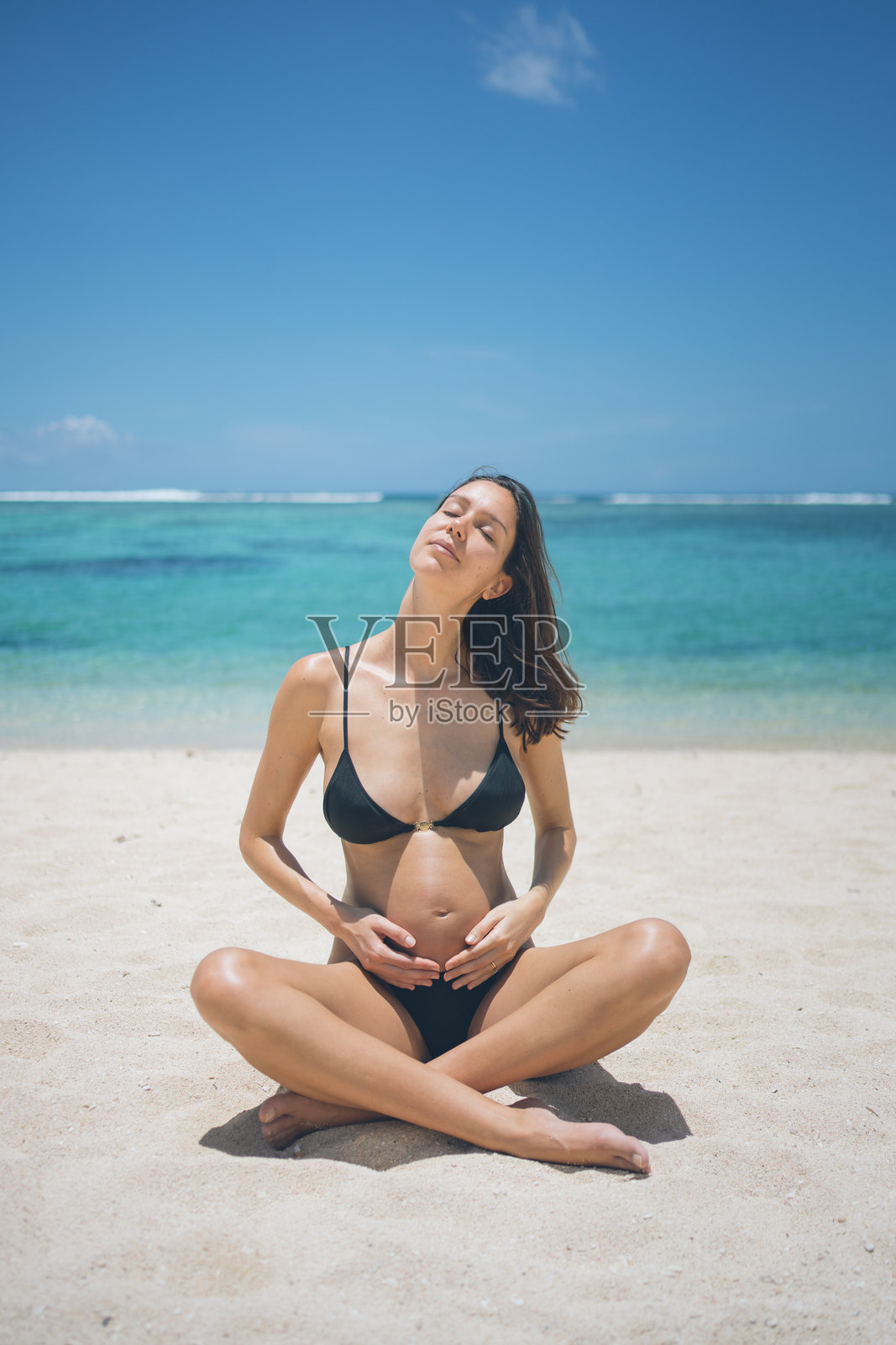 孕妇在热带海滩上抚摸着肚子照片摄影图片