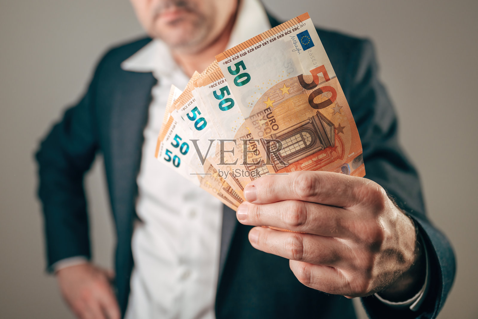 一名商人手持一叠50欧元纸币,象征着现金支付、收入、利润、财务成功、薪水、贷款或商业金融概念。照片摄影图片