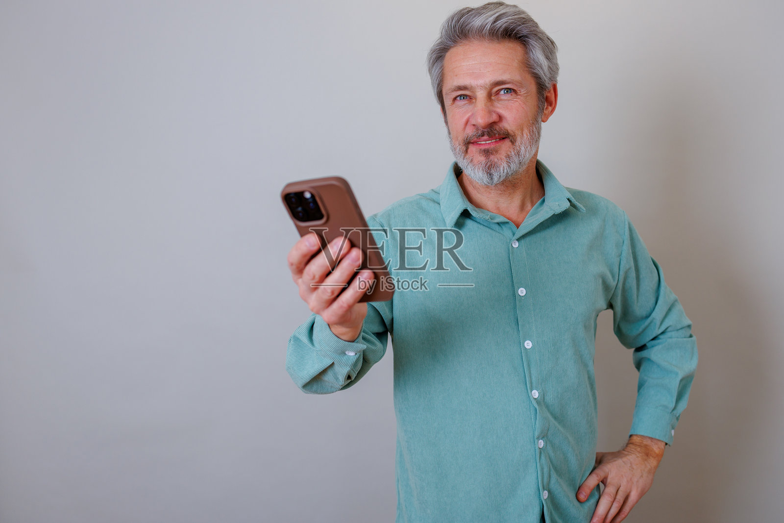 一位面带微笑的成熟男士,手持手机正在浏览,他友善地看向镜头。照片摄影图片