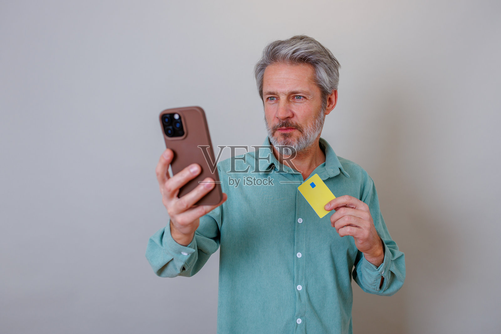 成熟男士手持智能手机和信用卡,进行安全的数字支付或在线购物照片摄影图片