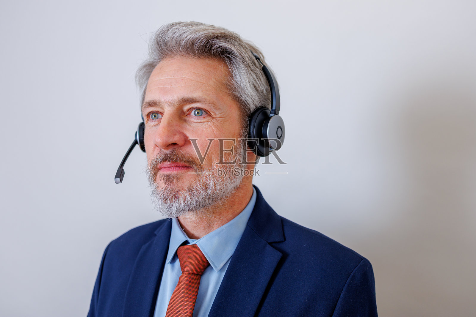 成熟的成年男性,戴着耳机,正在提供客户服务或在呼叫中心工作,看向别处照片摄影图片