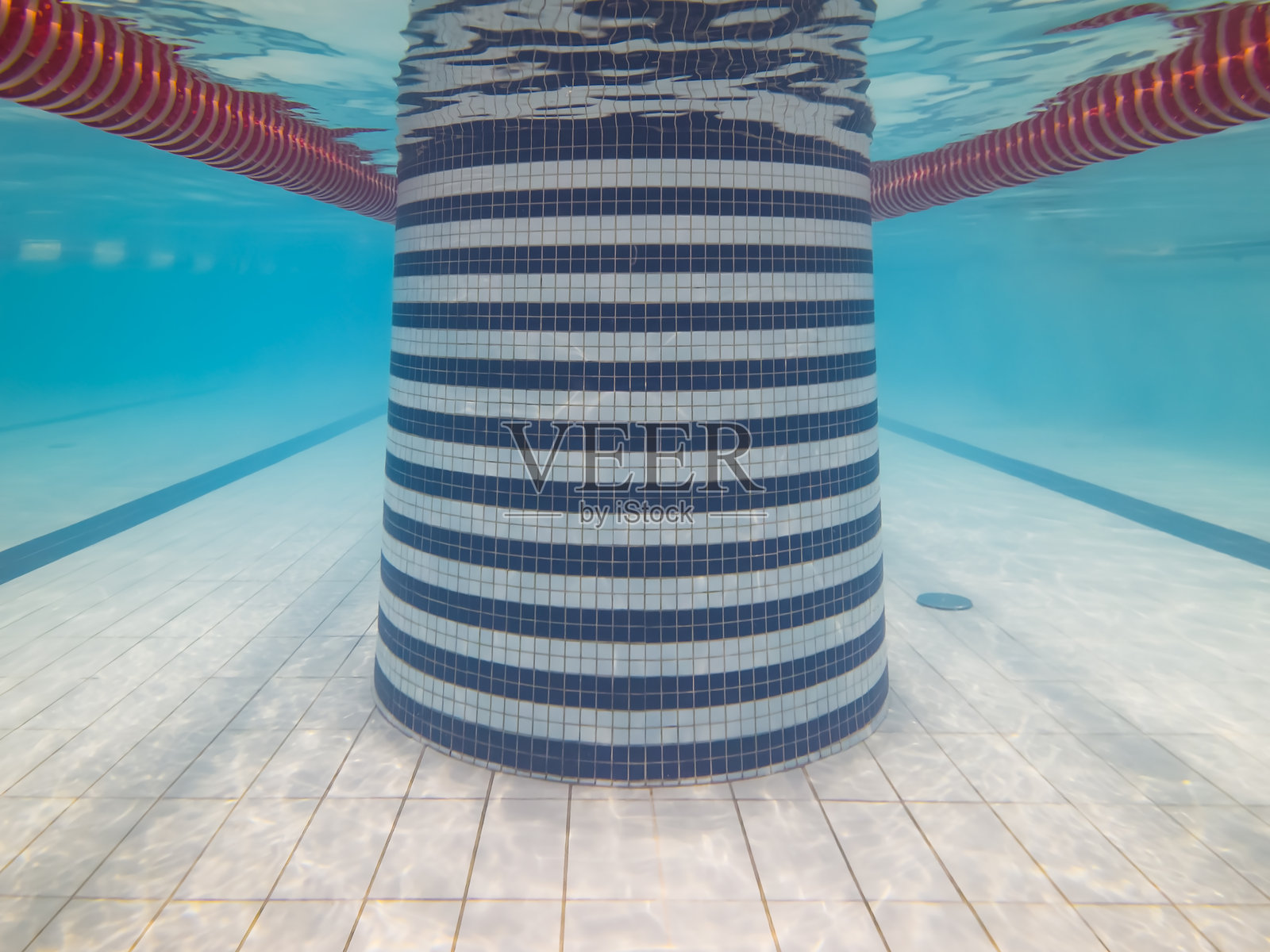 泳池内圆形瓷砖柱的水下视角,带有泳道线、蓝色水体和光线反射背景照片摄影图片