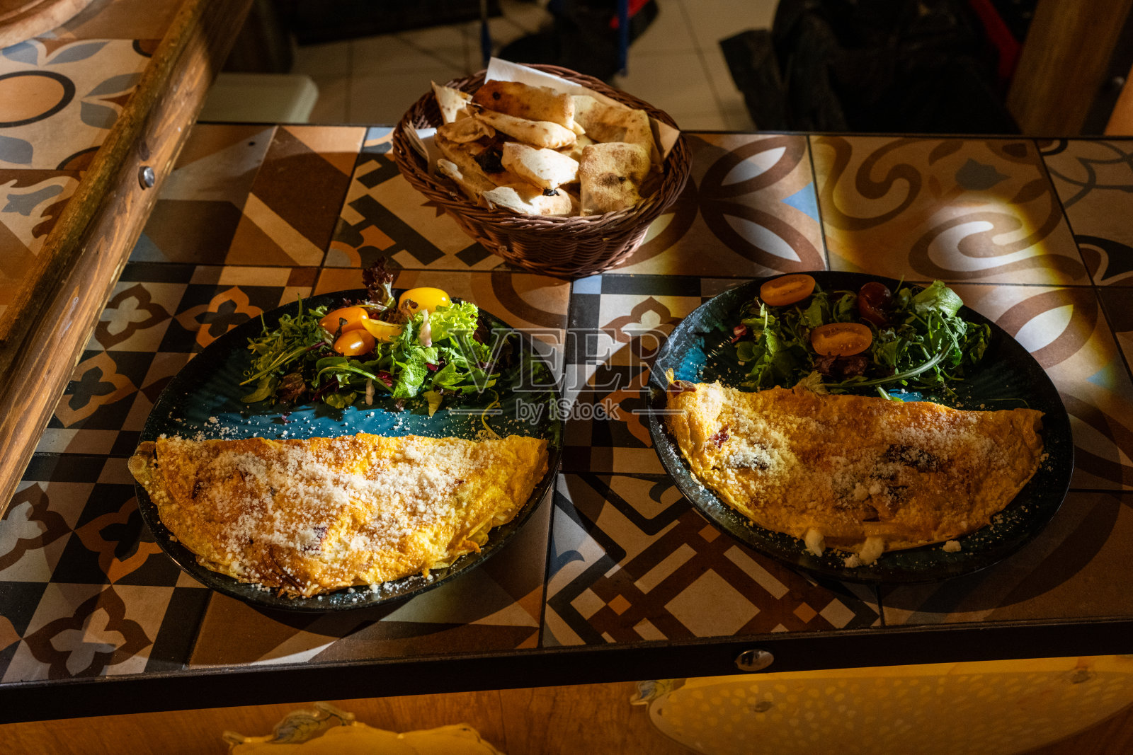 图案桌布上摆放着两份美味可口的法式薄饼,配有沙拉和面包篮照片摄影图片