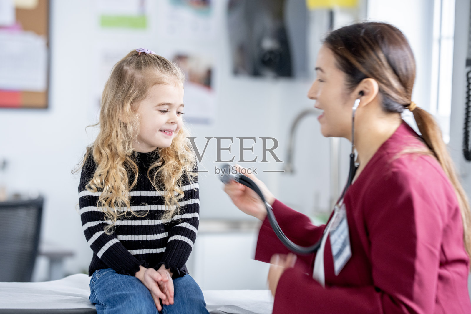 友好的医生在诊所为快乐的小女孩进行儿科检查照片摄影图片