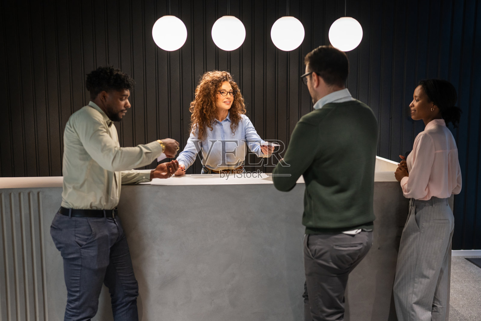 人们在接待处与一位微笑的女士互动照片摄影图片