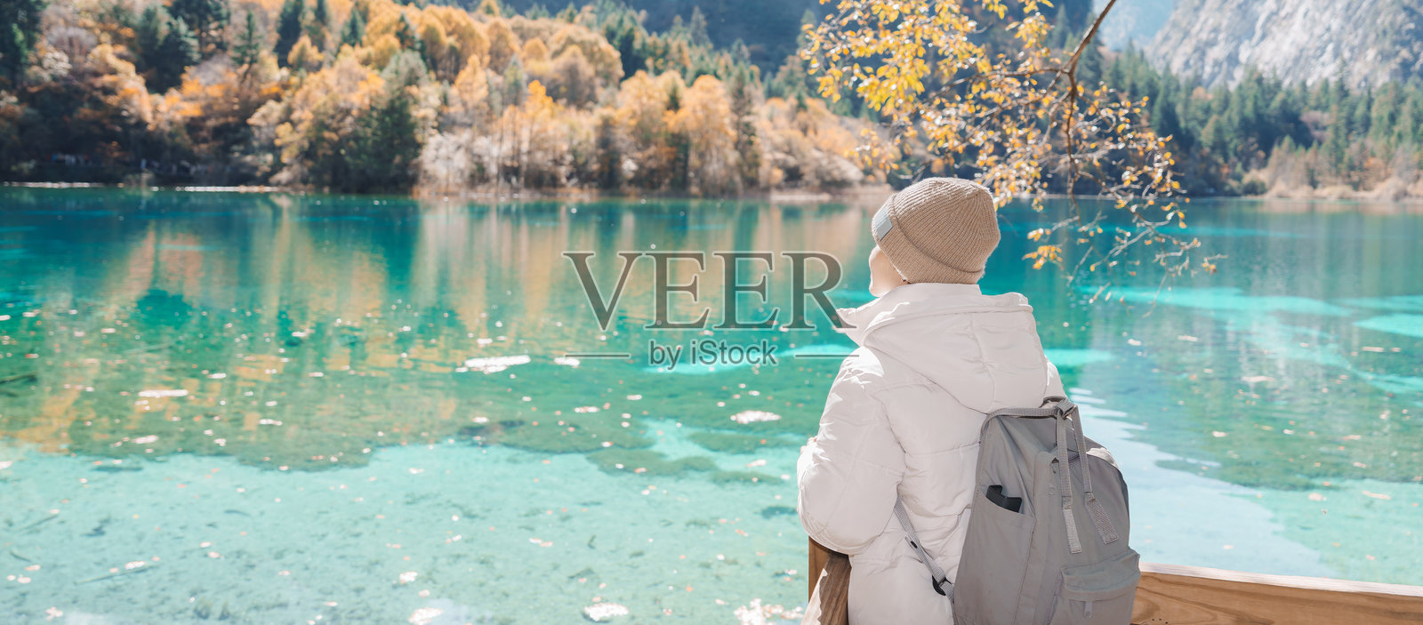 快乐的女游客在中国四川九寨沟国家公园旅行。秋季,游客正在游览五花海和雪山。这是成都附近的一个著名地标和度假胜地。照片摄影图片