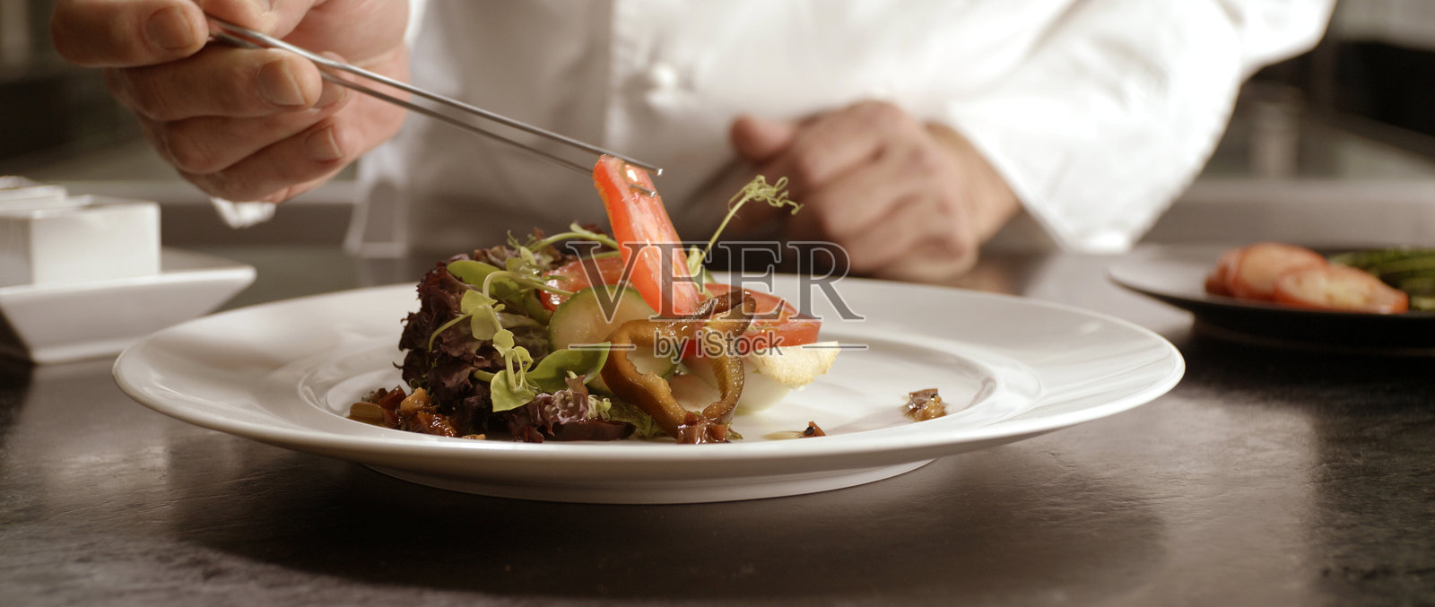 厨师正小心翼翼地为美味的沙拉摆盘照片摄影图片