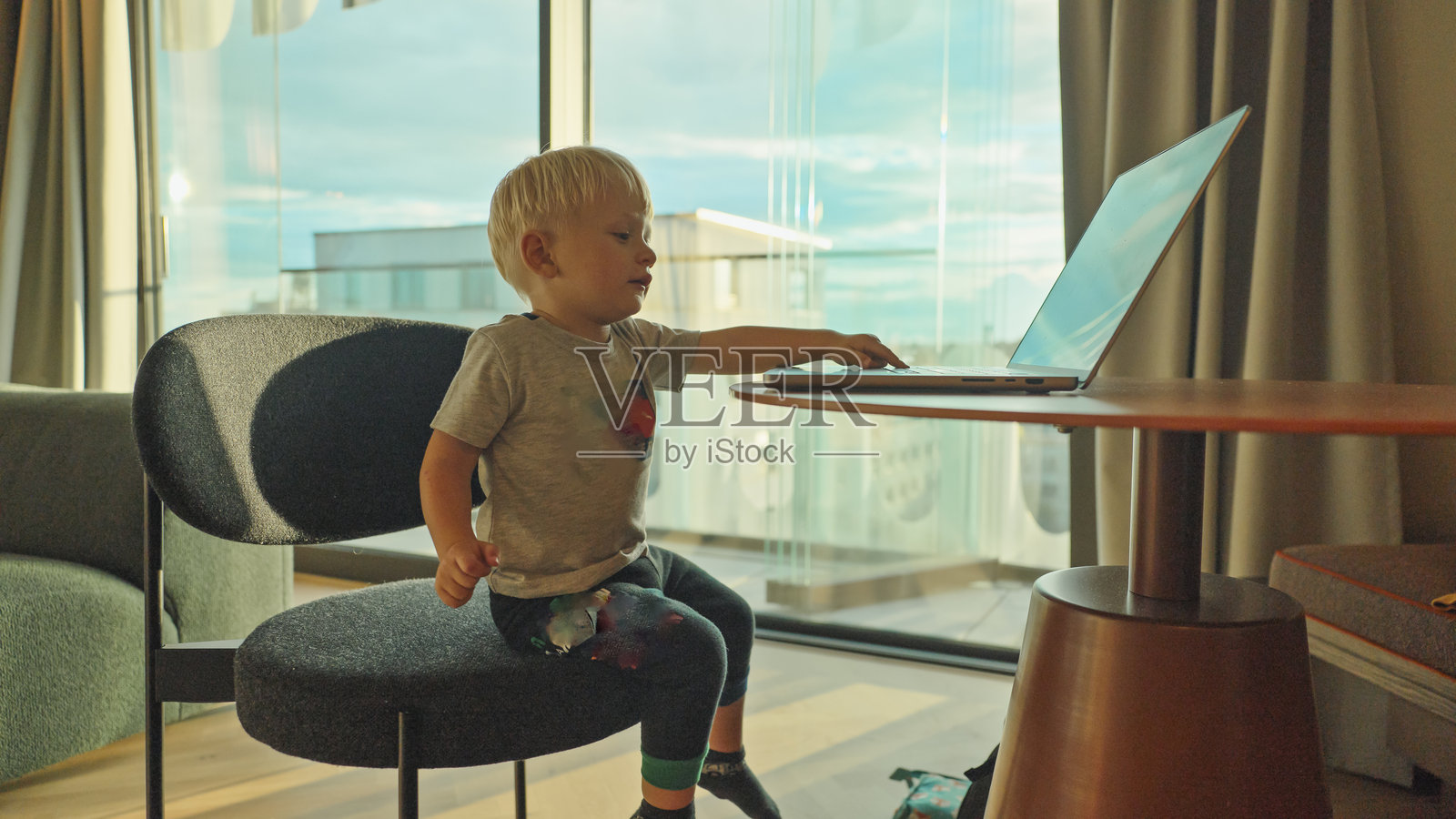 白人男孩在时尚公寓里快乐地假装在笔记本电脑上打字照片摄影图片