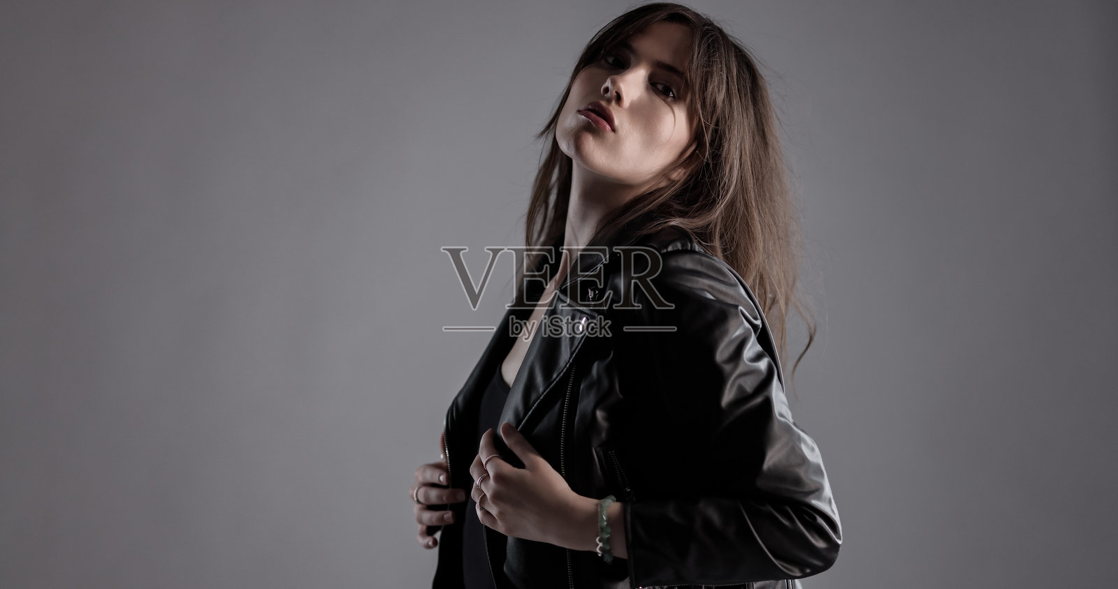 自信的年轻女性身穿皮夹克摆姿势照片摄影图片