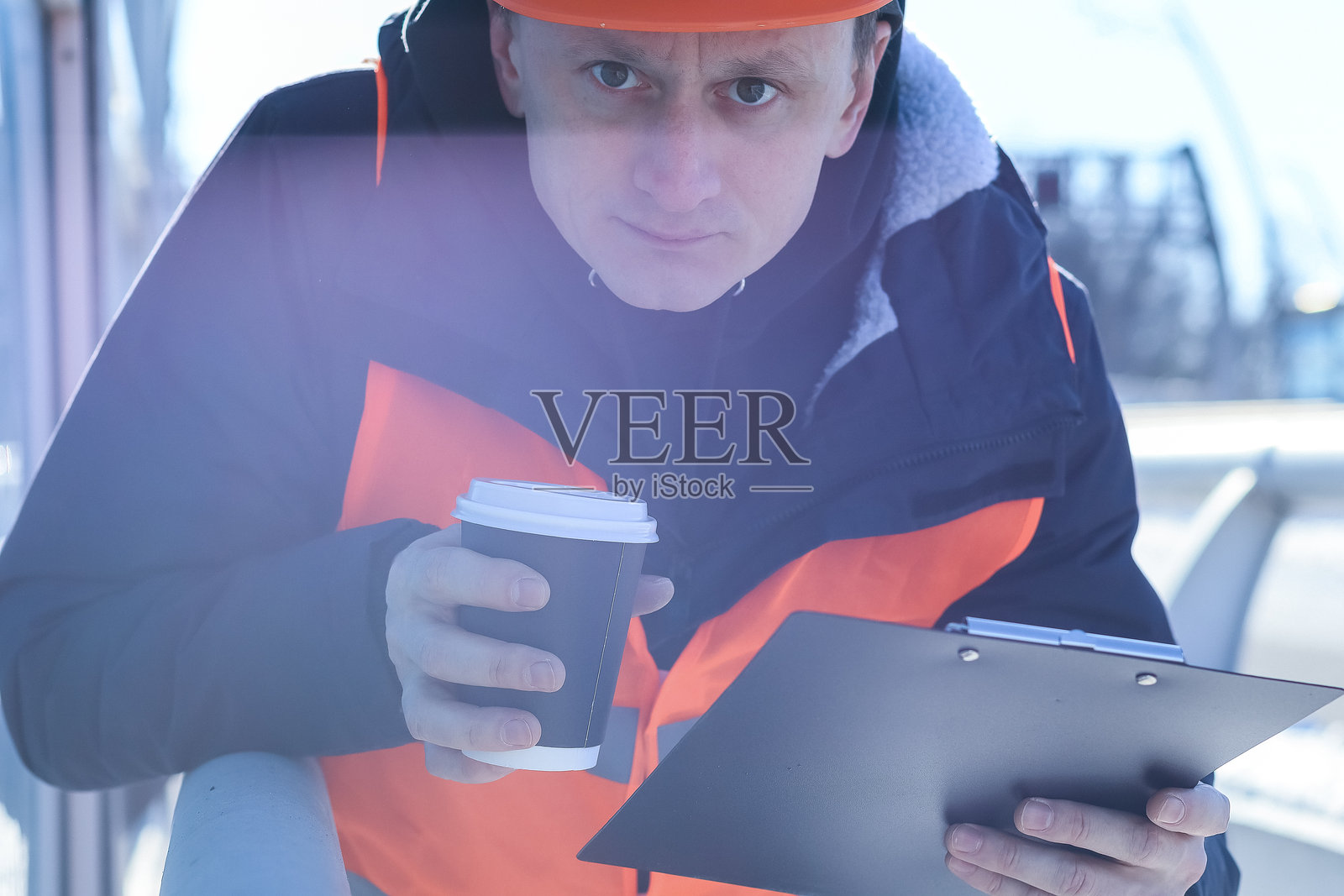 俯视角度拍摄的工人在工地上查看带有咖啡的剪贴板照片摄影图片