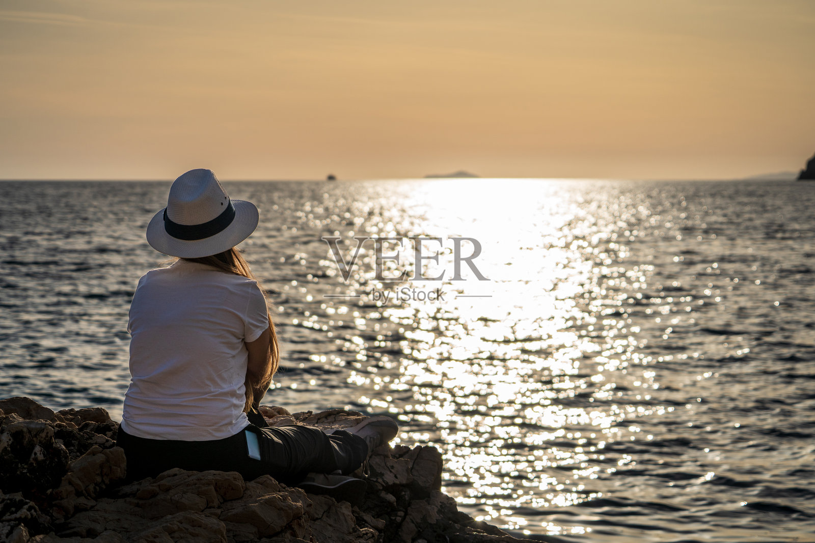 游客坐在亚得里亚海岸边欣赏日落照片摄影图片