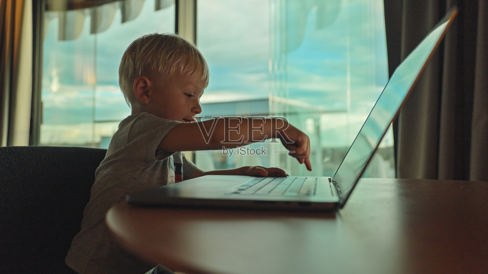 公寓里,一个年轻活泼的男孩假装在笔记本电脑上工作照片摄影图片