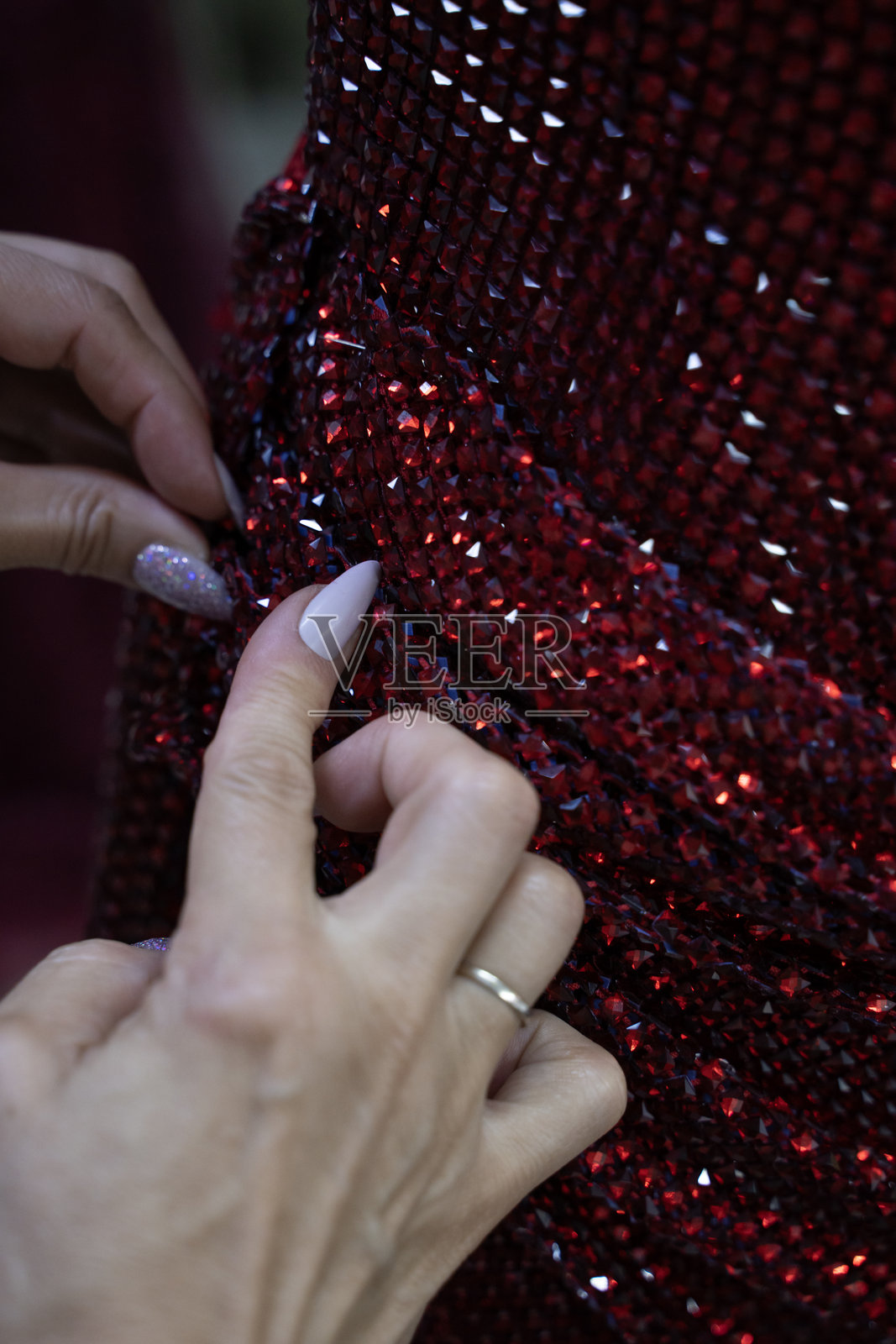 一位裁缝正在缝制一条红色的晚礼服。照片摄影图片