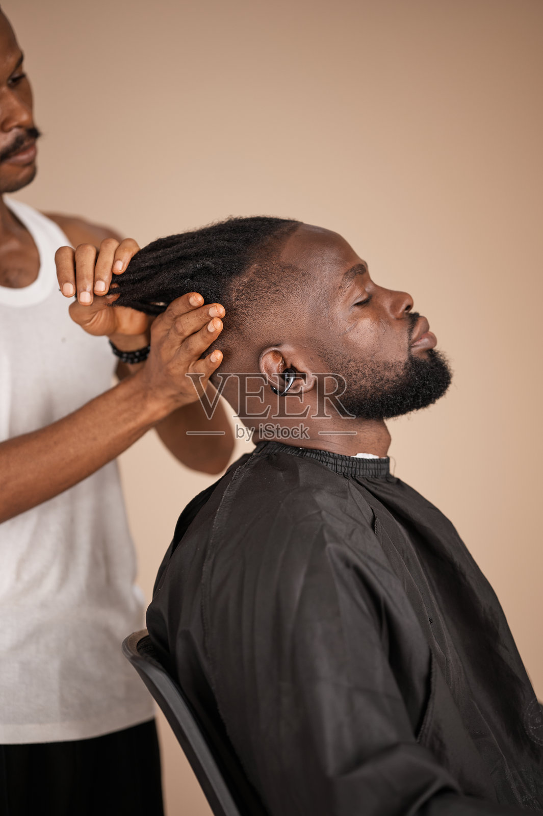年轻的尼日利亚理发师在理发时整理脏辫照片摄影图片