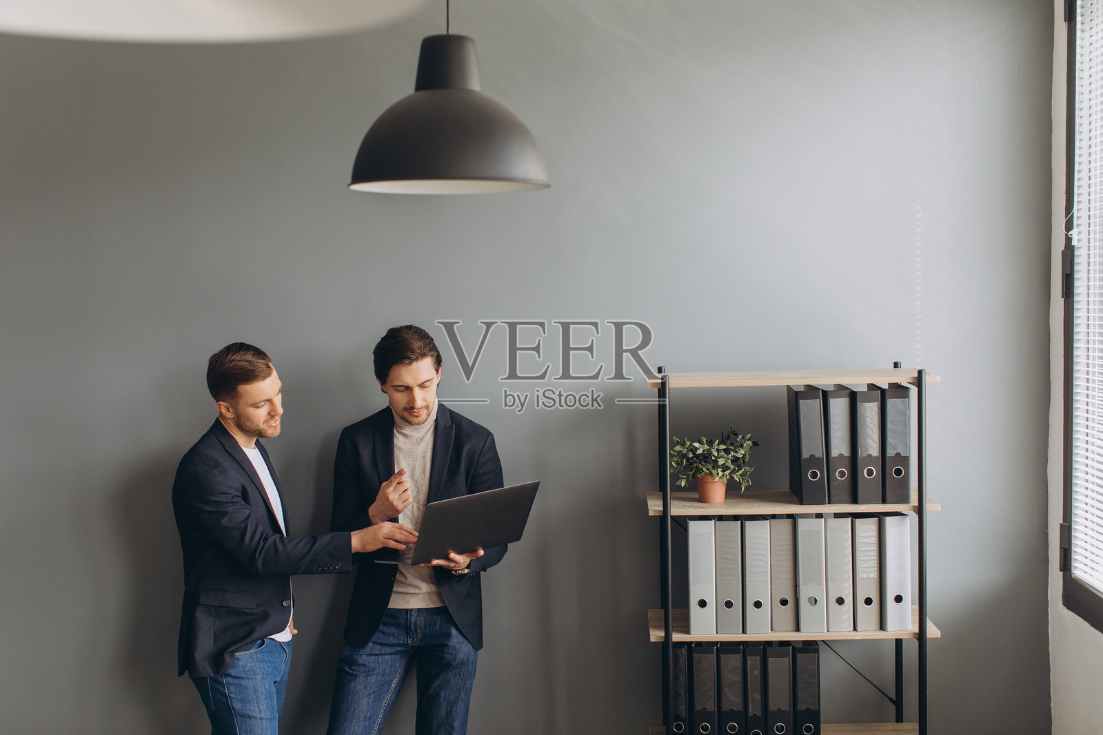 商务人士在现代办公室的笔记本电脑上协作,讨论项目策略和创新想法照片摄影图片